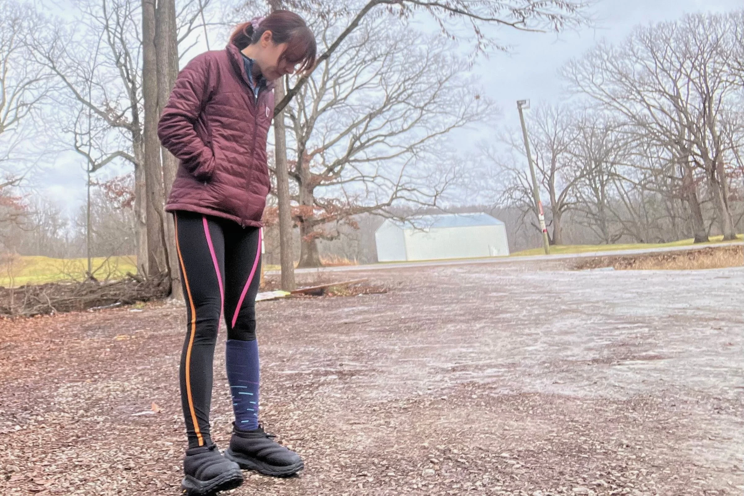   Woman standing in a gravel lot wearing the HOKA Kaha 2 Frost Moc GTX  