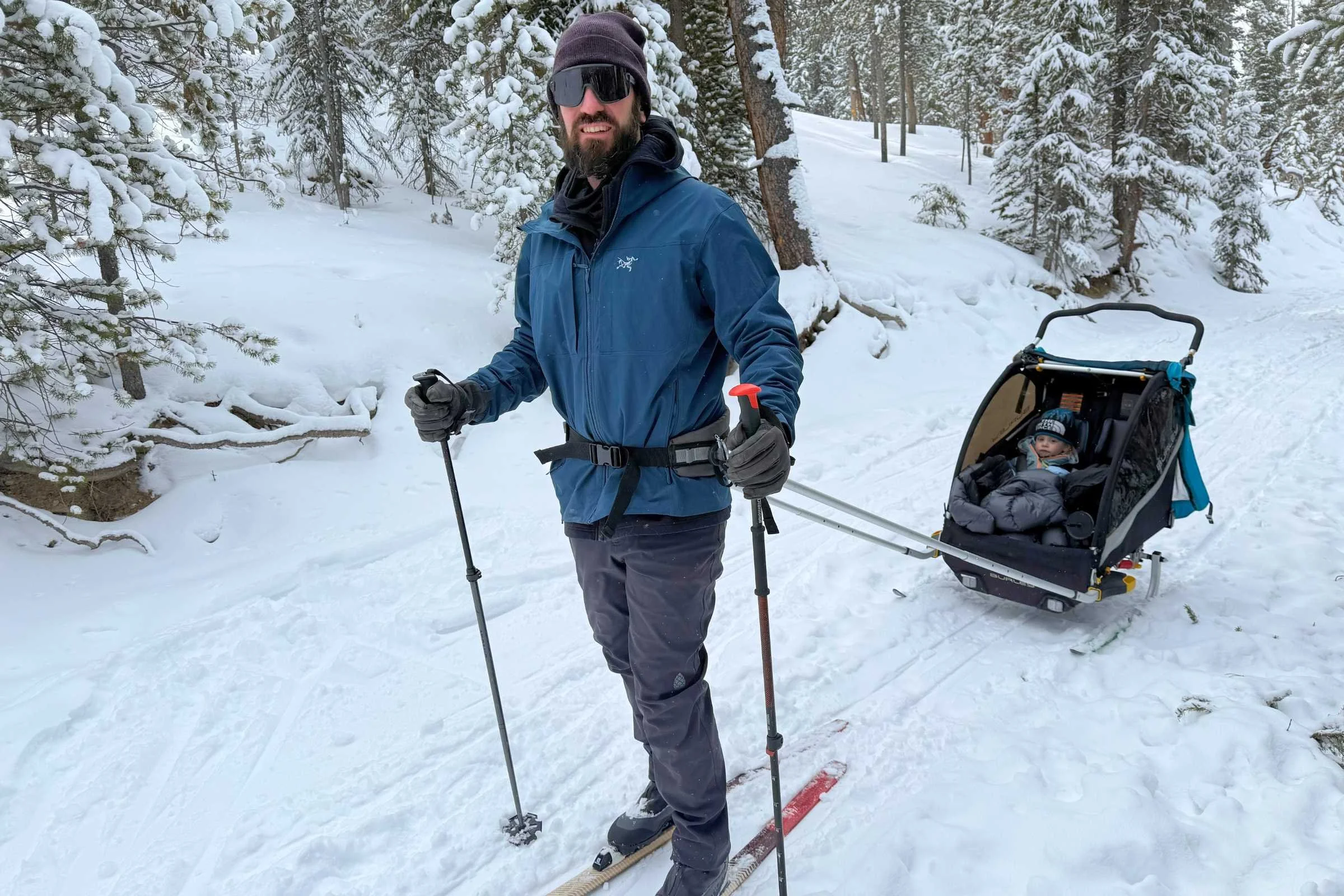   Skier wearing Stio Pinedale pants pulling sled on snowy trail  