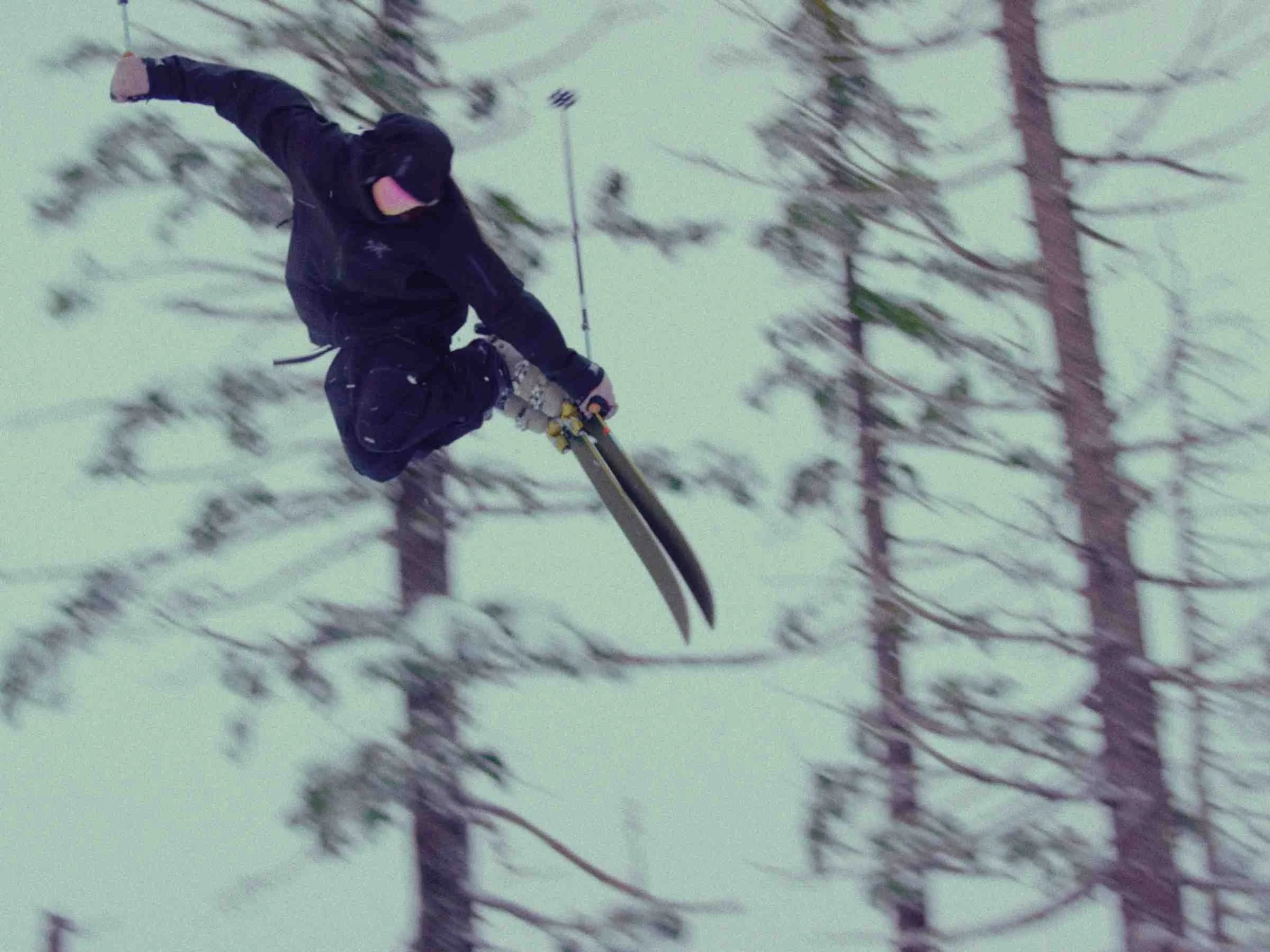   Skier jumping wearing Arc'teryx Sabre jacket with trees in the back ground   