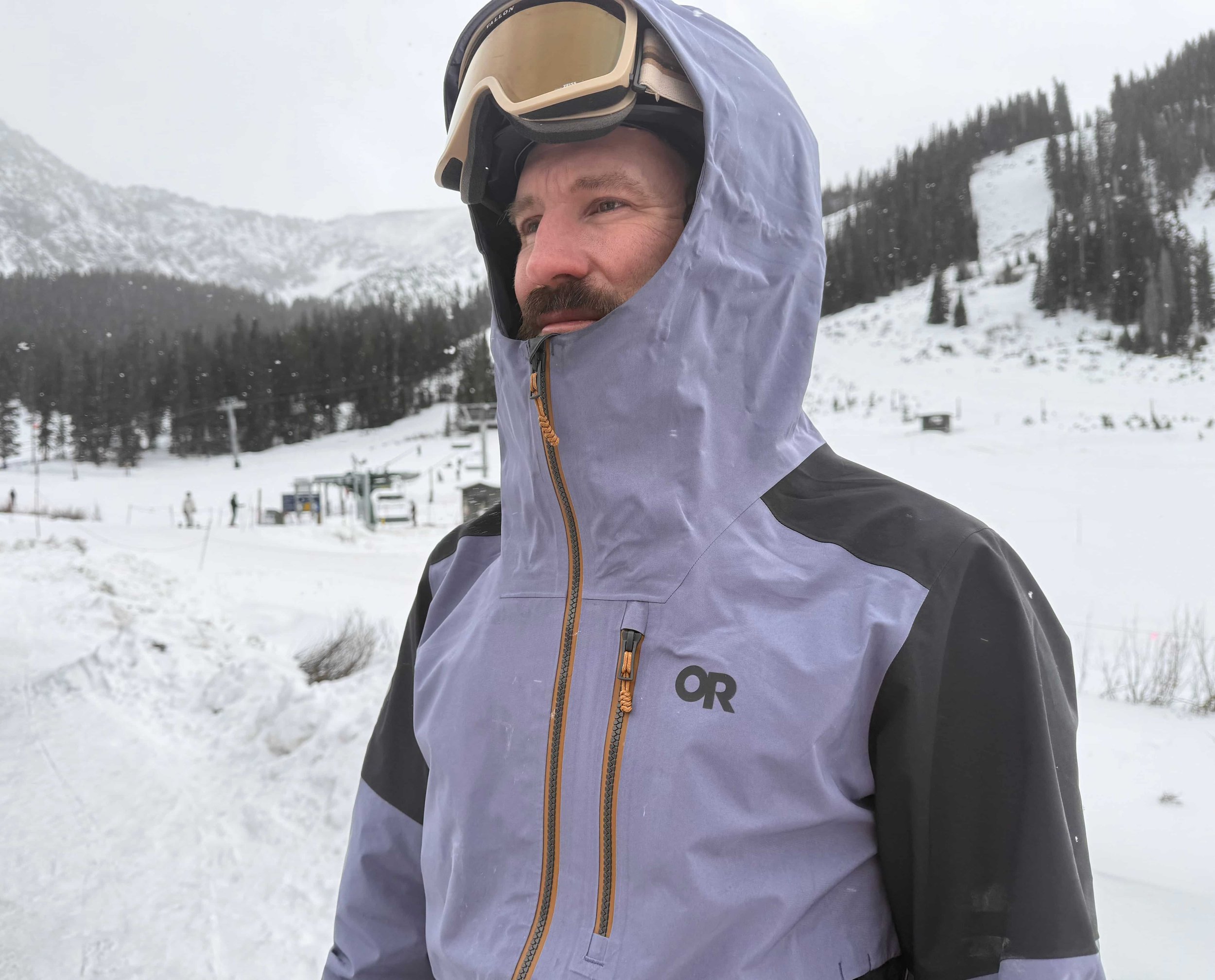   Man wearing Outdoor Research Hemispheres ski jacket with hood up  
