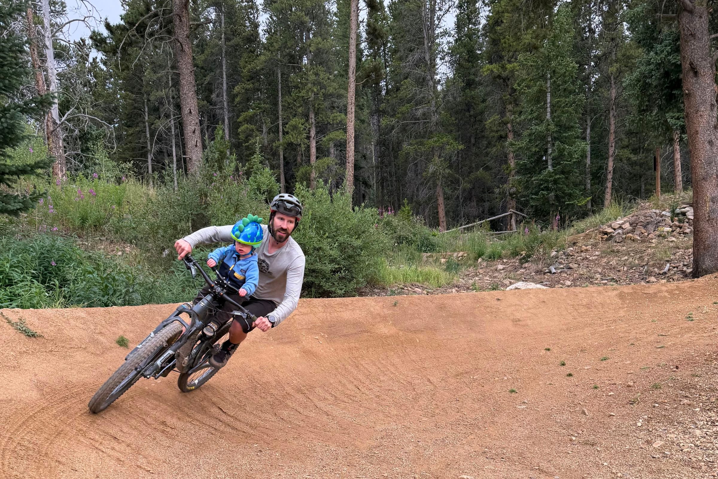 Adult and child cycling together on a dirt trail, using the Kids Ride Shotgun Shotgun Pro Evo.