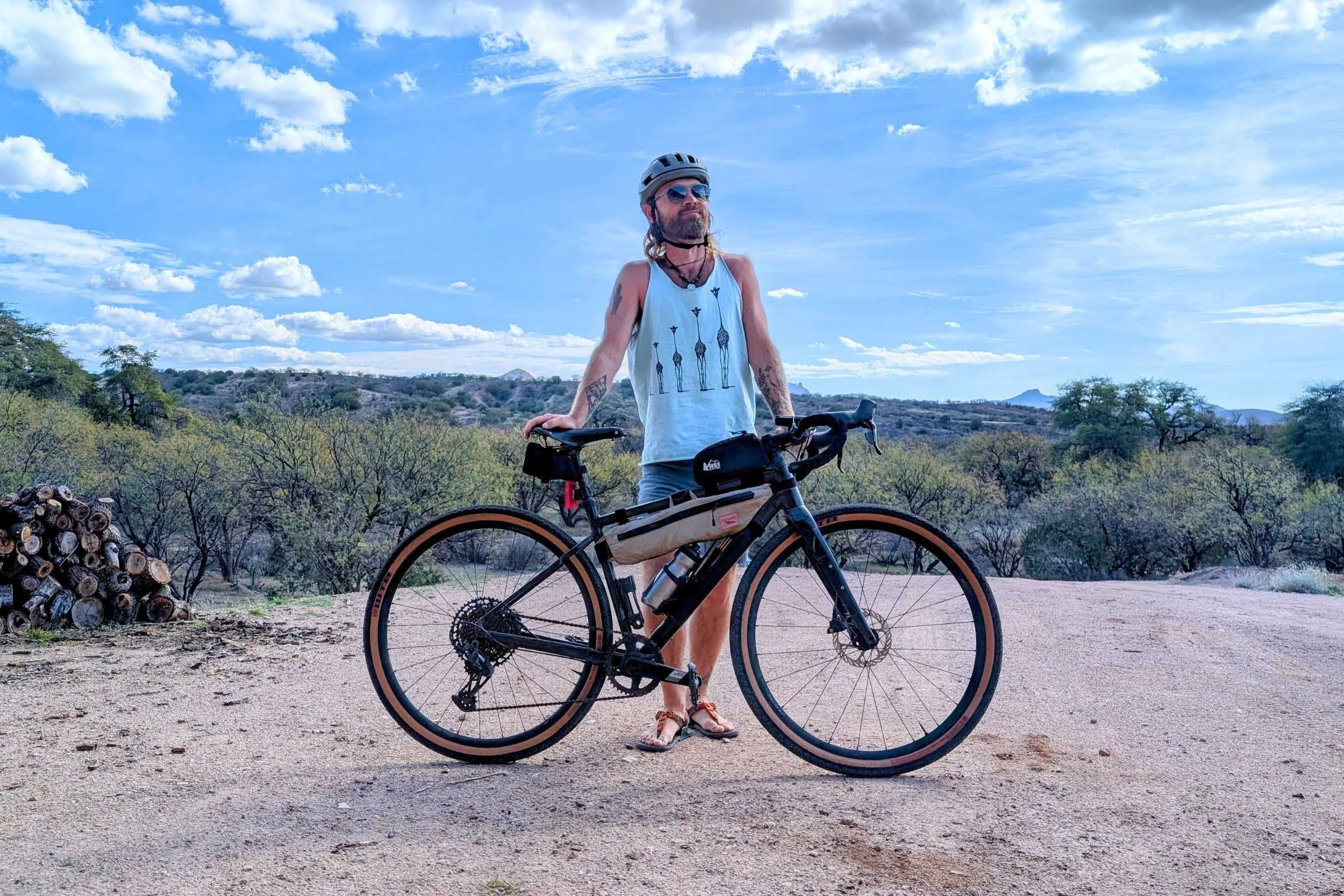  Cyclist standing next to a gravel bike outfitted with frame bags including a Junction Top Tube Bag in a desert landscape.  