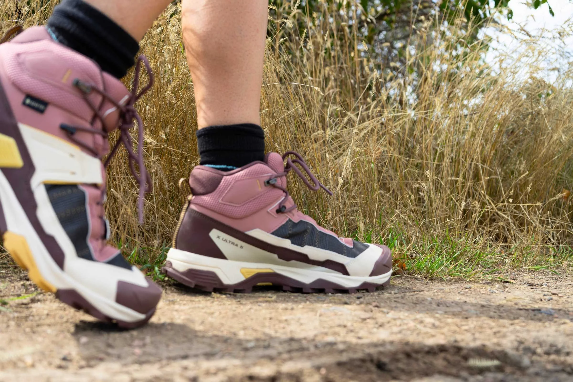   A person wearing the Salomon X Ultra 5 Mid GTX hiking boots while walking on a dirt trail  