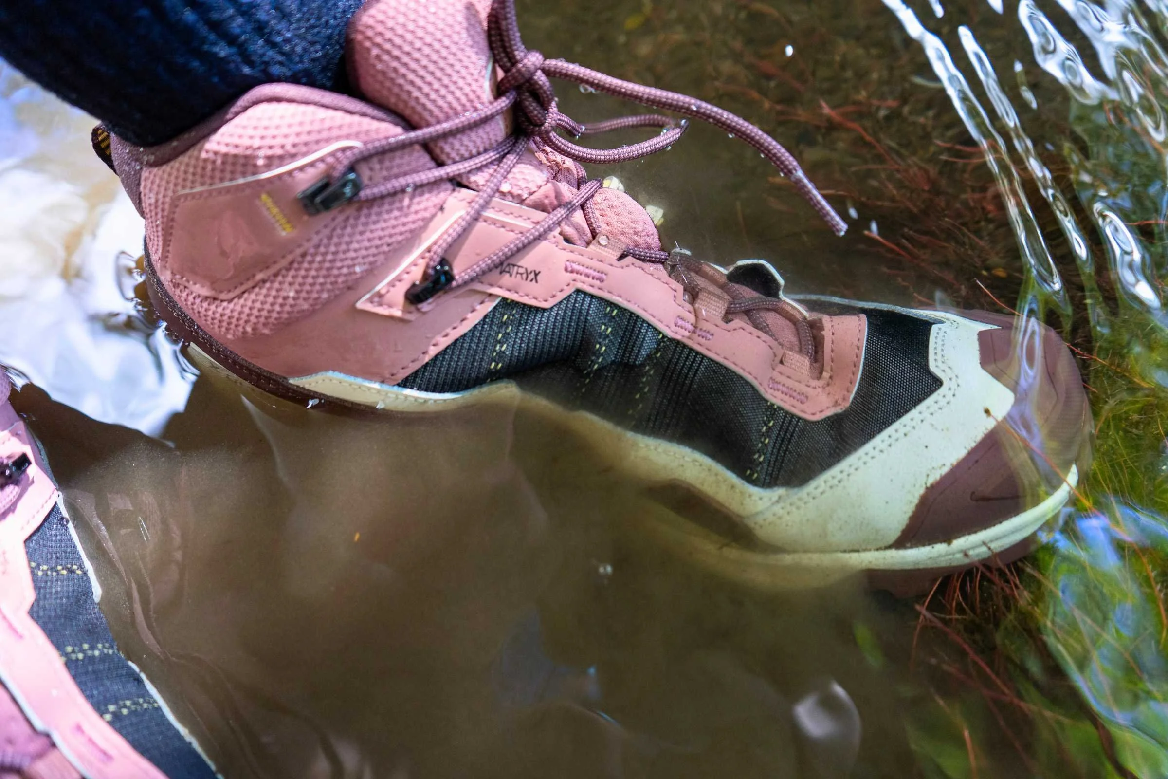   The Salomon X Ultra 5 Mid GTX hiking boot stepping into shallow water to demonstrate waterproof performance  
