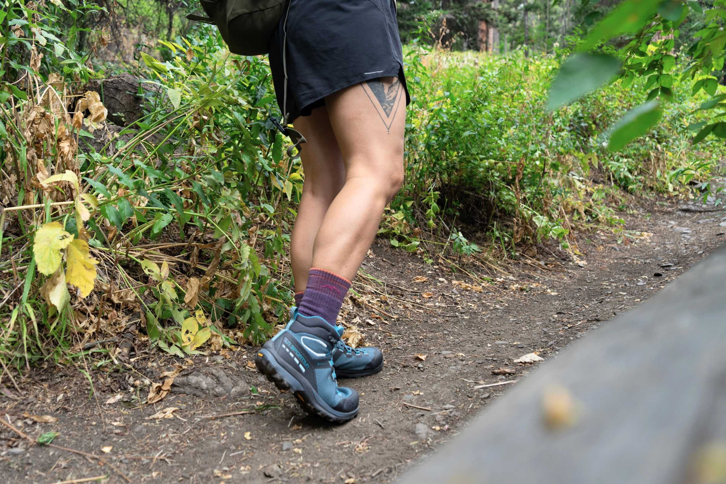   A person walking on a forest trail wearing the La Sportiva TX Hike Mid GTX hiking boots  