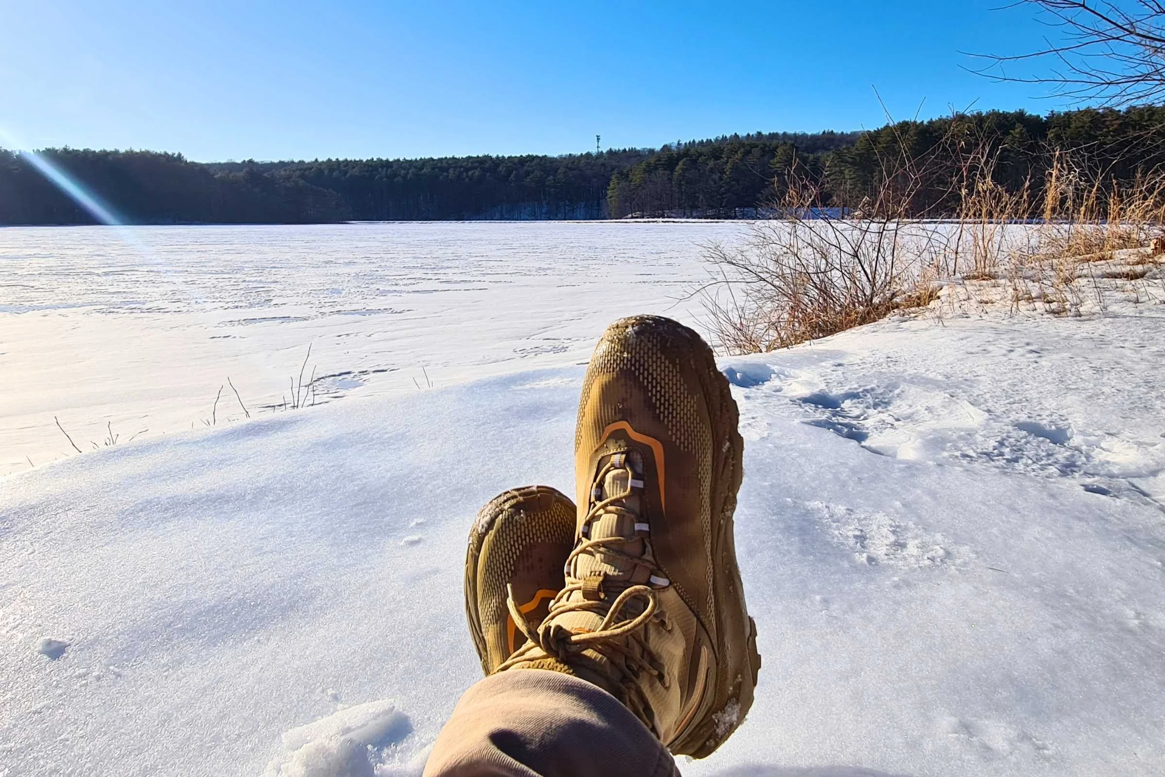   A person with their feet kicked up, showing the HOKA Kaha 2 Frost GTX hiking boots in a snowy landscape  