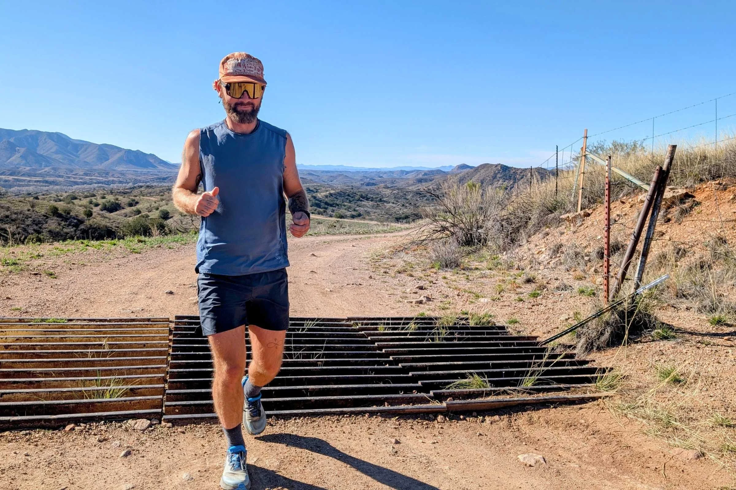   Man trail running on a dusty path wearing REI Swiftland shorts in a dry mountain landscape.  