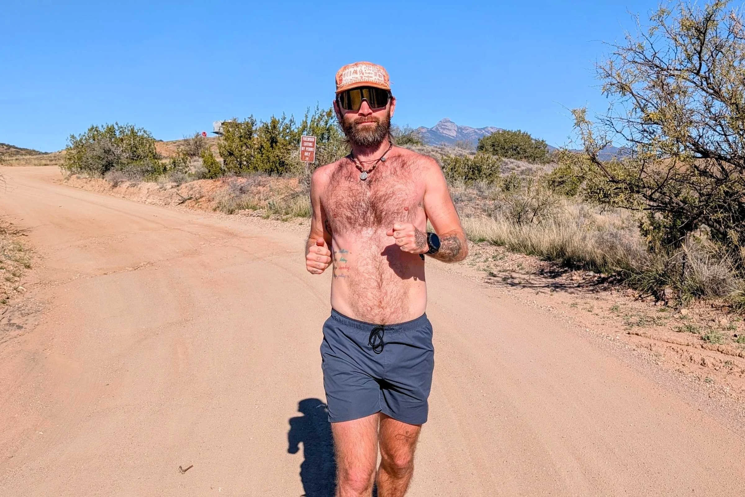   Man running on a dirt road in REI Swiftland shorts during a trail run in a desert setting.  