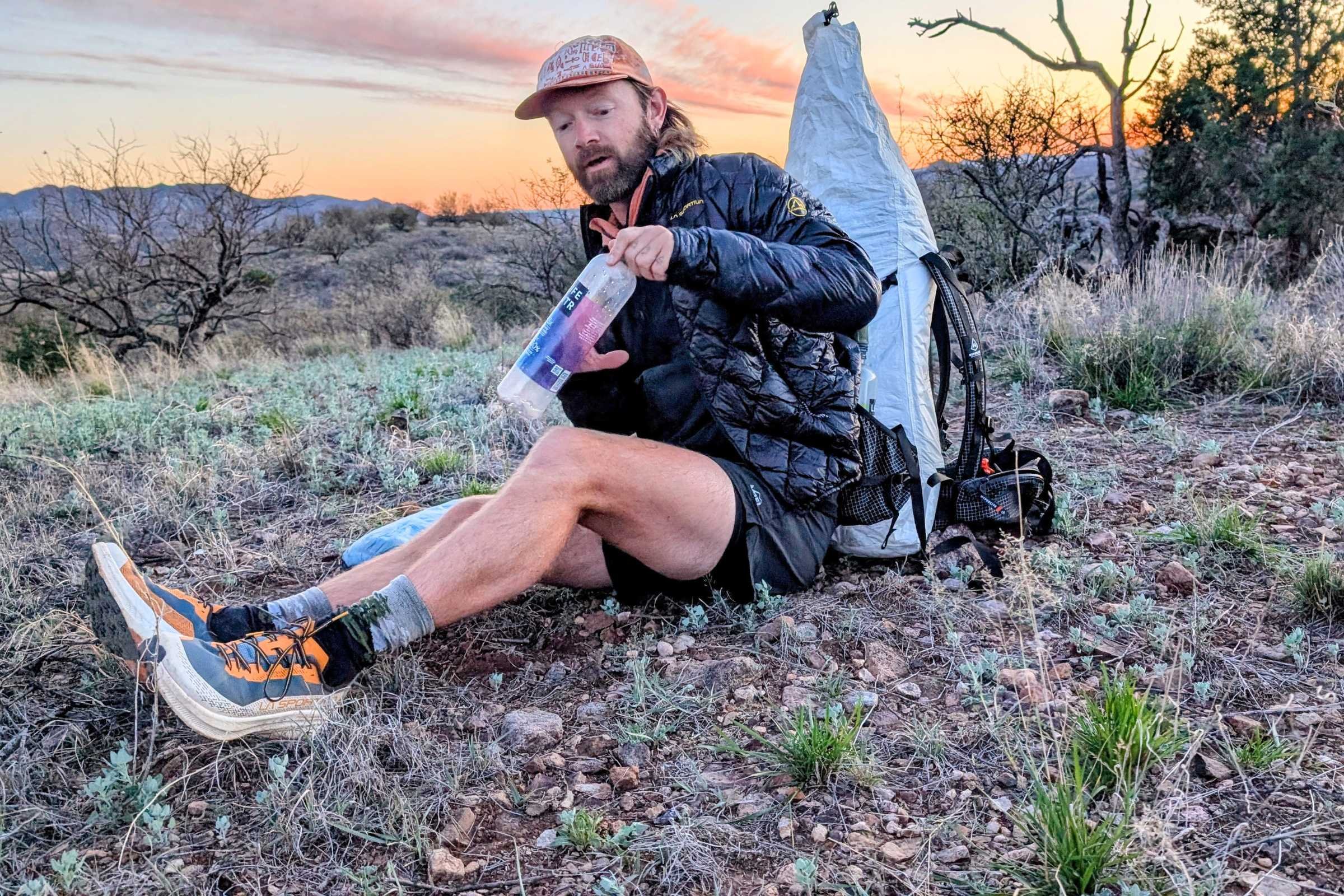   Man seated on the trail wearing the La Sportiva Prodigio 2 trail running shoes during a backcountry outing at sunset.  