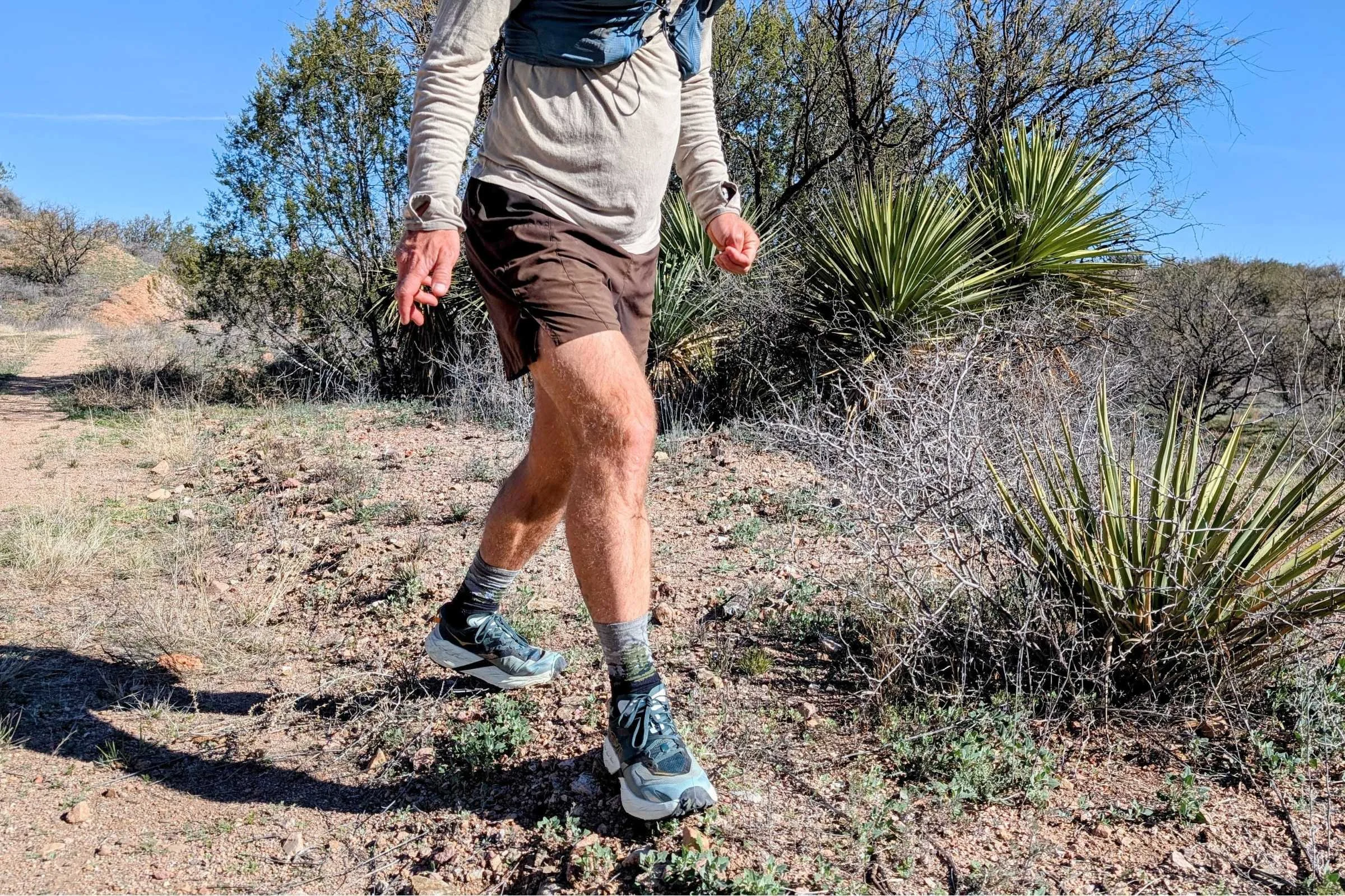   Close-up action shot of the HOKA Speedgoat 7 trail running shoes moving over rugged desert trail.  