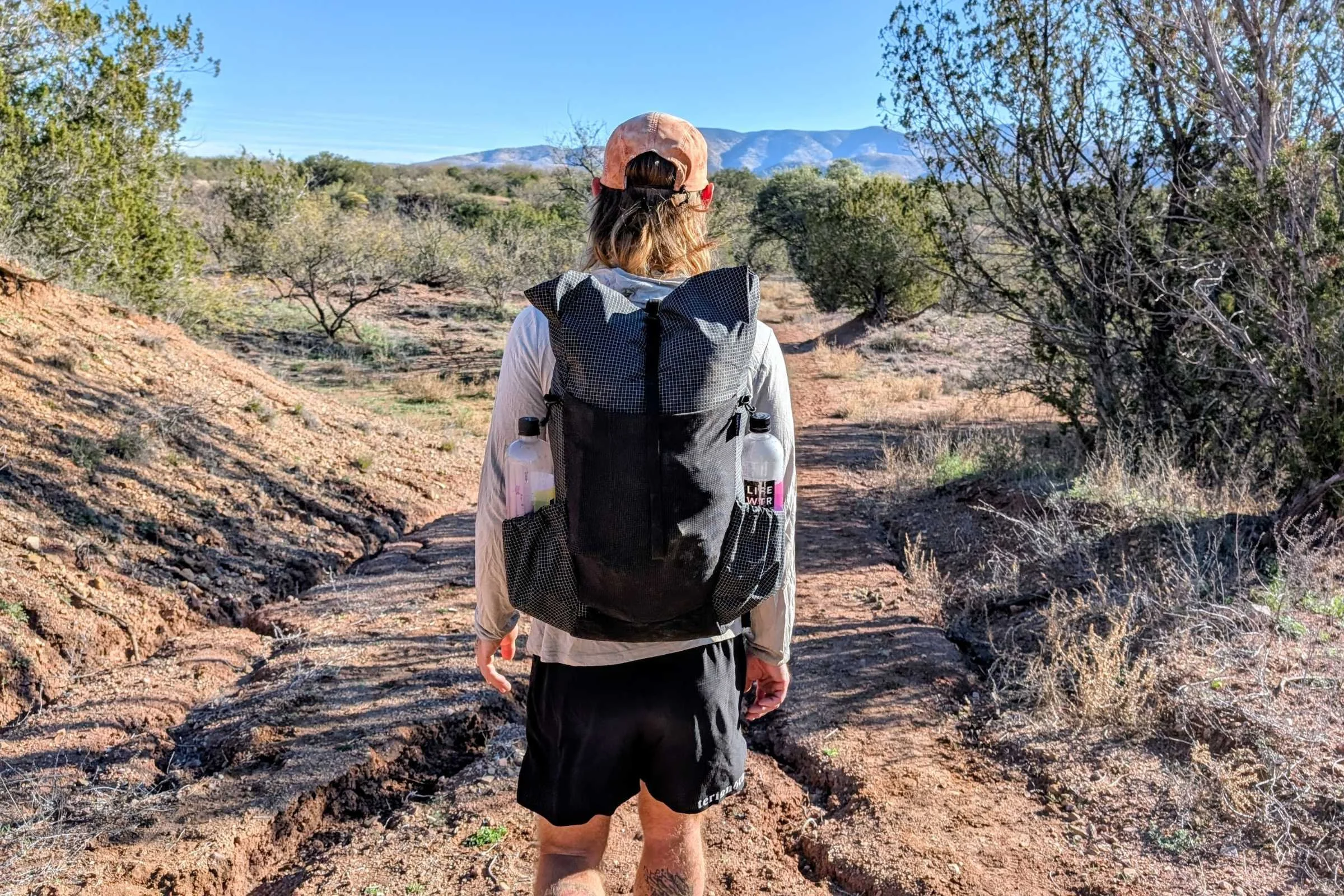   Rear view of a runner wearing the Pa’lante Packs V2 with Joey Straps on a desert trail.  
