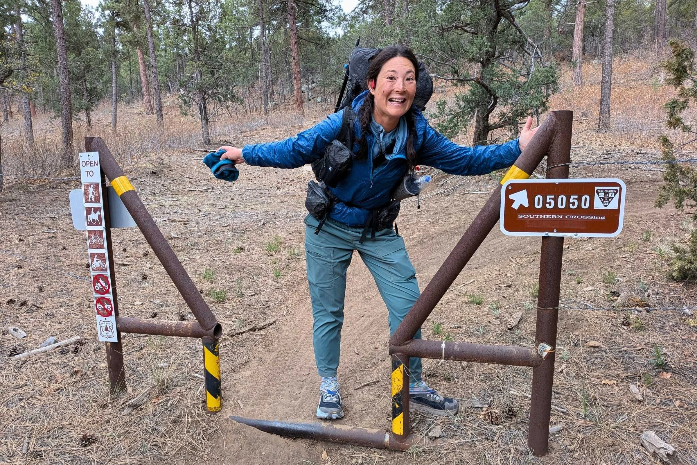   Hiker by a trail gate wearing REI Trailmade Pull-On pants  