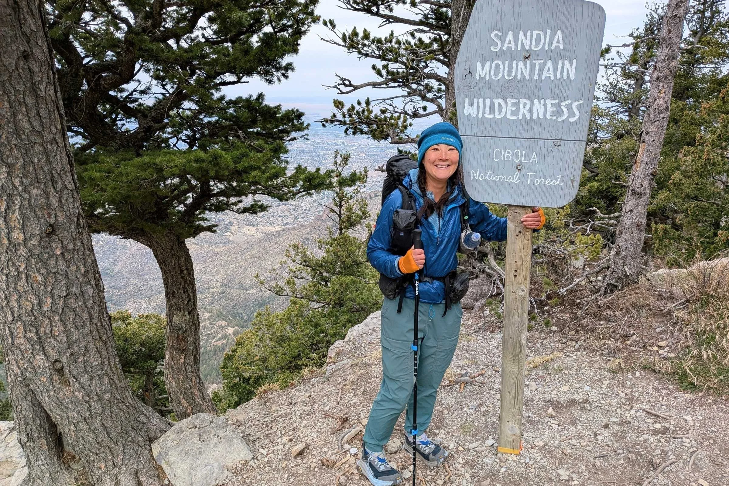   Hiker standing by a trail sign wearing REI Trailmade Pull-On pants.  
