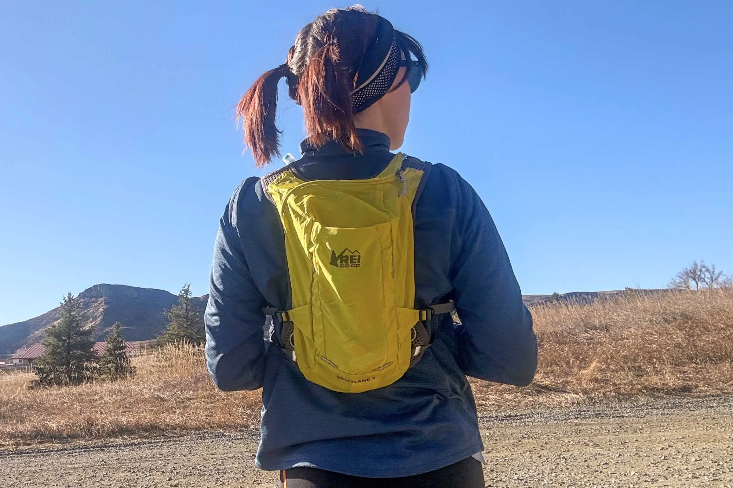   Rear view of a runner wearing the REI Co-op Swiftland 5 Hydration Vest on a trail.  