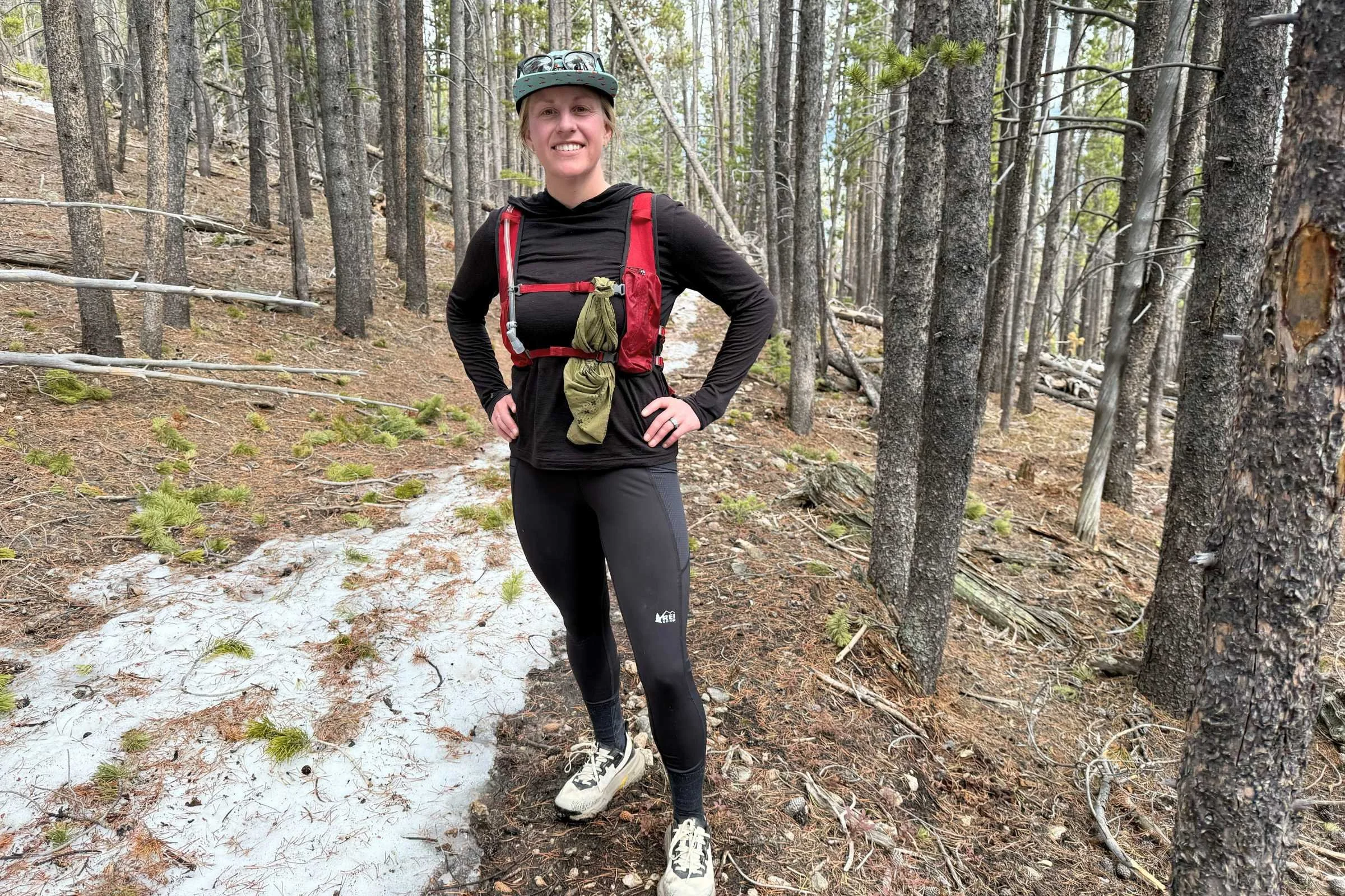   Woman standing next to a snowy forest trail wearing REI Co-op Swiftland 7/8 Running Tights.  