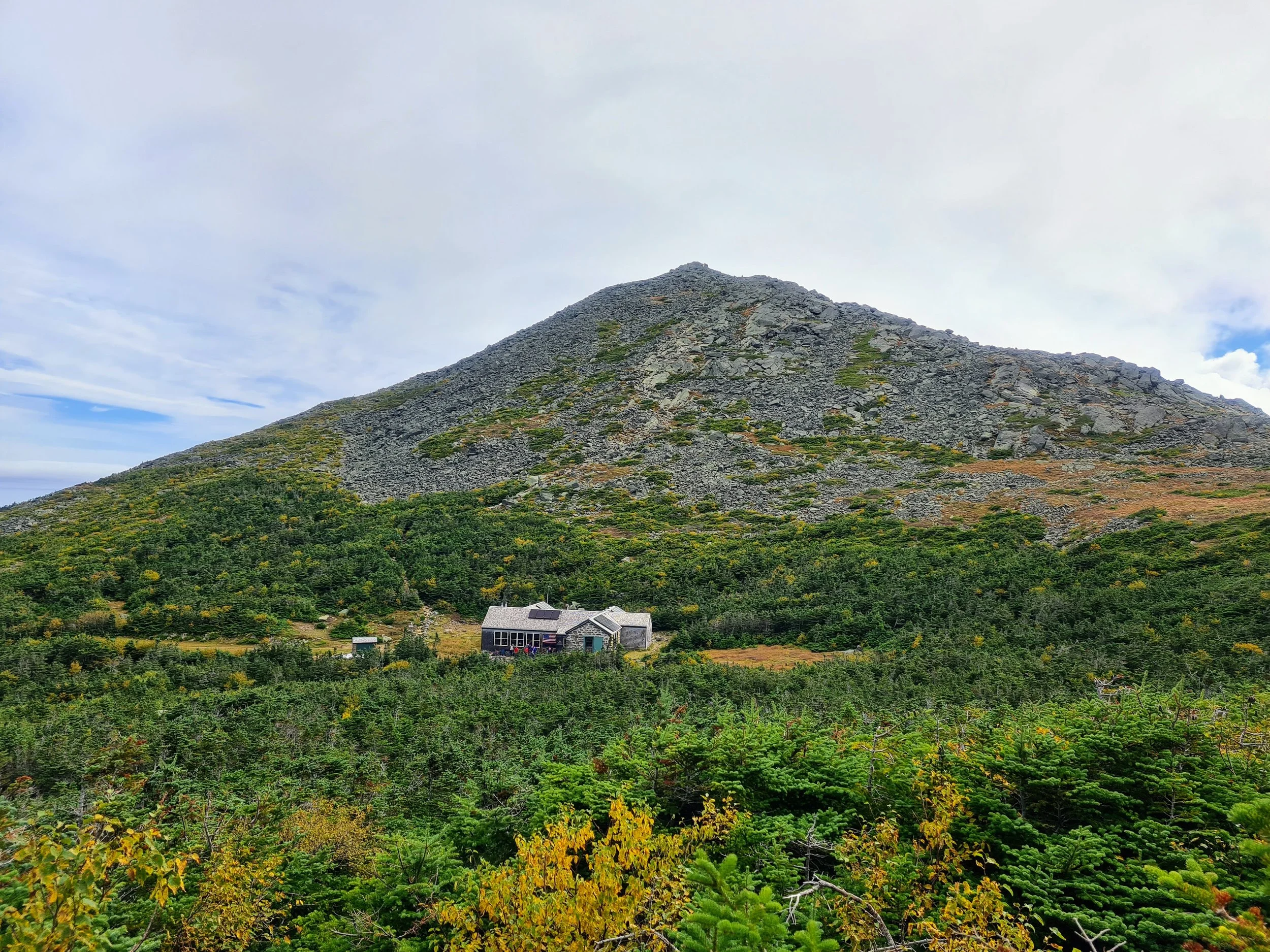  View of Mt. Madison and Madison Spring Hut along the Presidential Traverse under a cloudy blue sky. 
