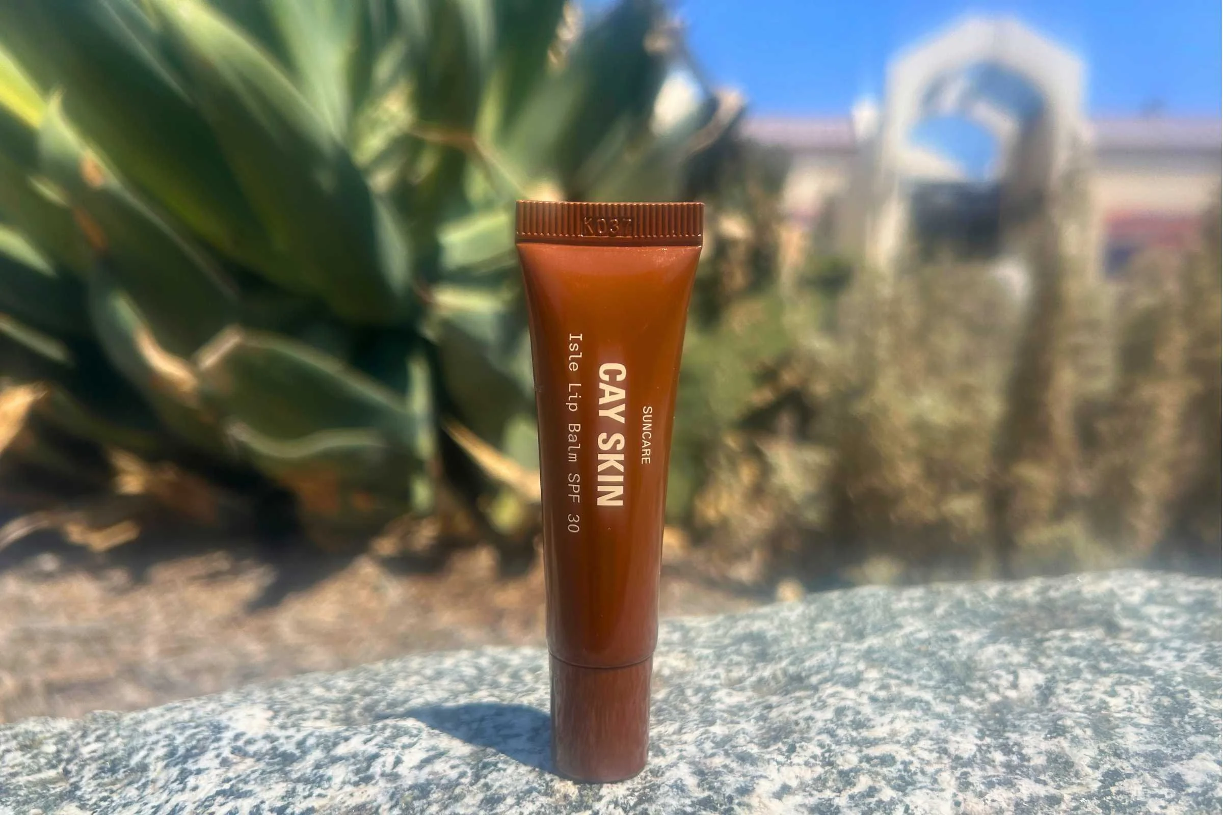   Cay Skin Isle Lip Balm SPF 30 displayed outdoors in sunny garden setting  