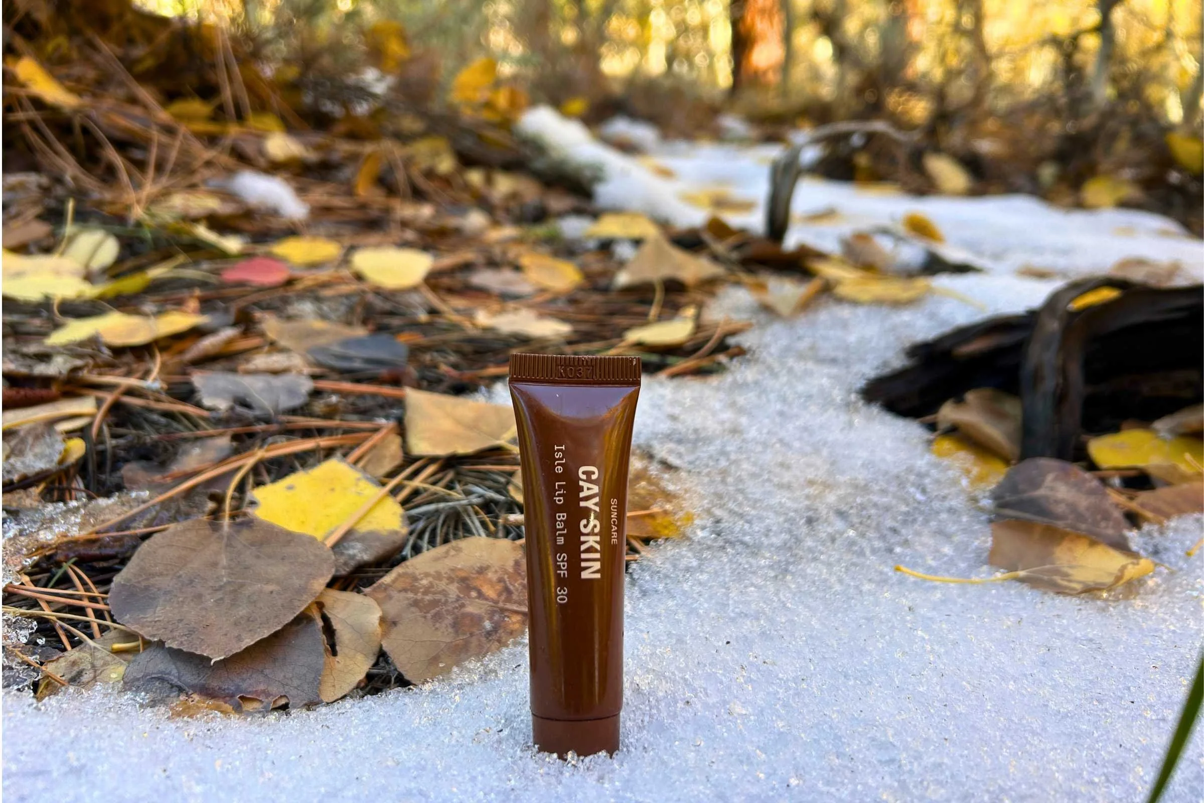   Cay Skin Isle Lip Balm SPF 30 standing in snow and autumn leaves during outdoor SPF testing  