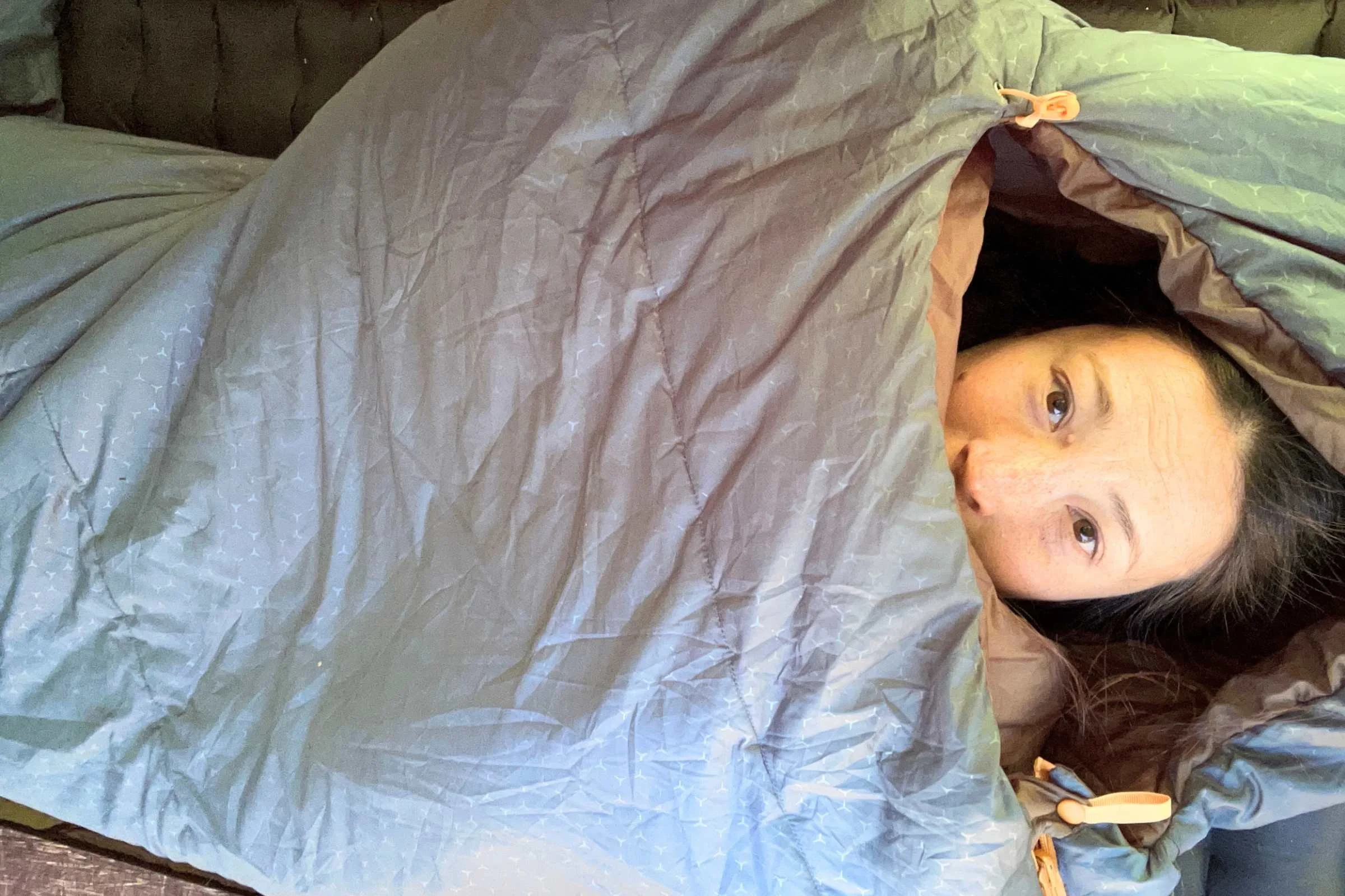   Camper inside Exped DeepSleep sleeping bag during overnight camping comfort testing  