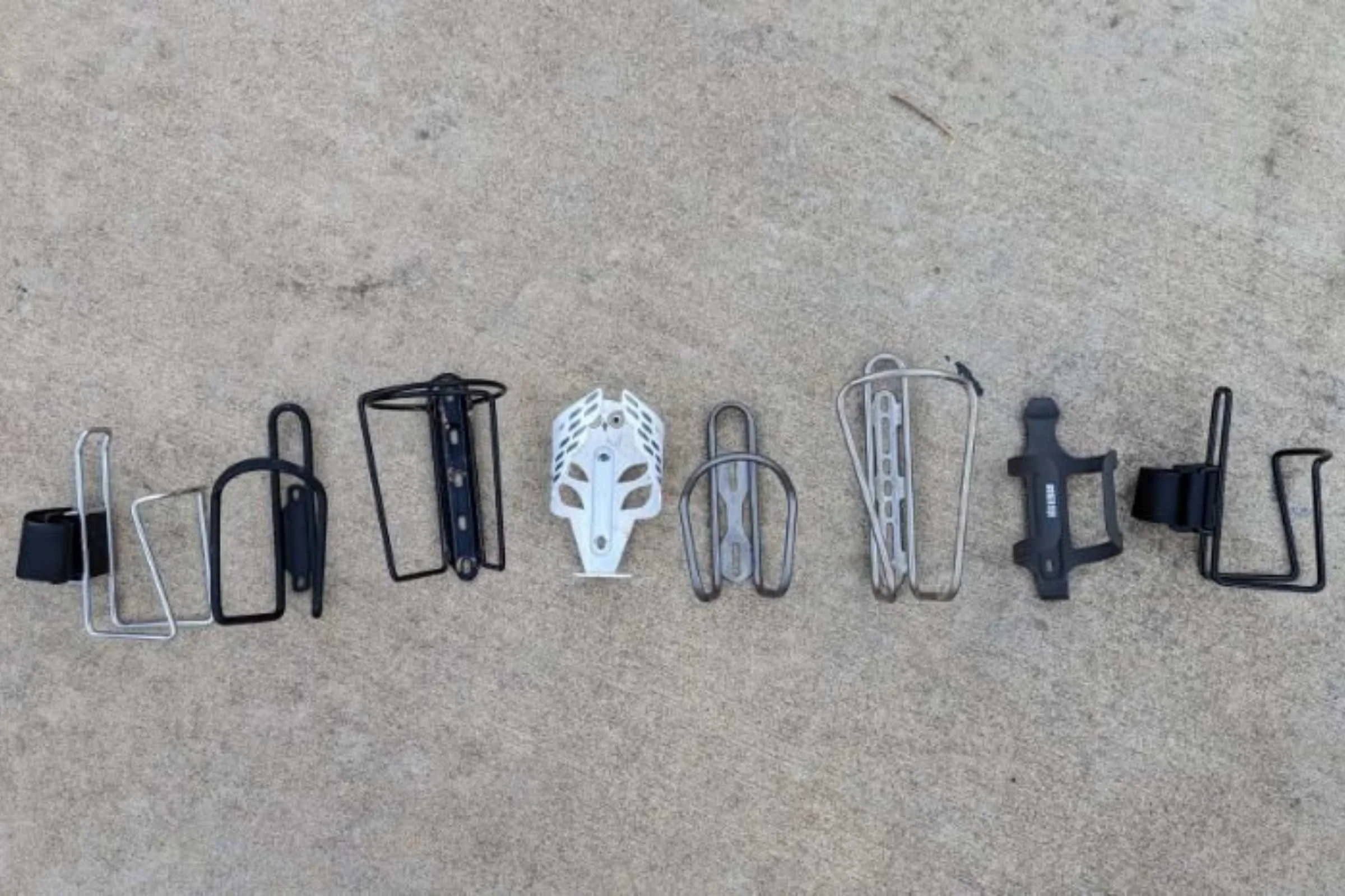   Water bottle cages we tested. From left to right: TwoFish quick cage stainless steel,&nbsp;Planet Bike Aluminum,&nbsp;Velo Orange Mojave,&nbsp;Portland Design Works Owl Cage,&nbsp;Silca Sucuro,&nbsp;Widefoot Litercage,&nbsp;REI Junction Bottle Cage