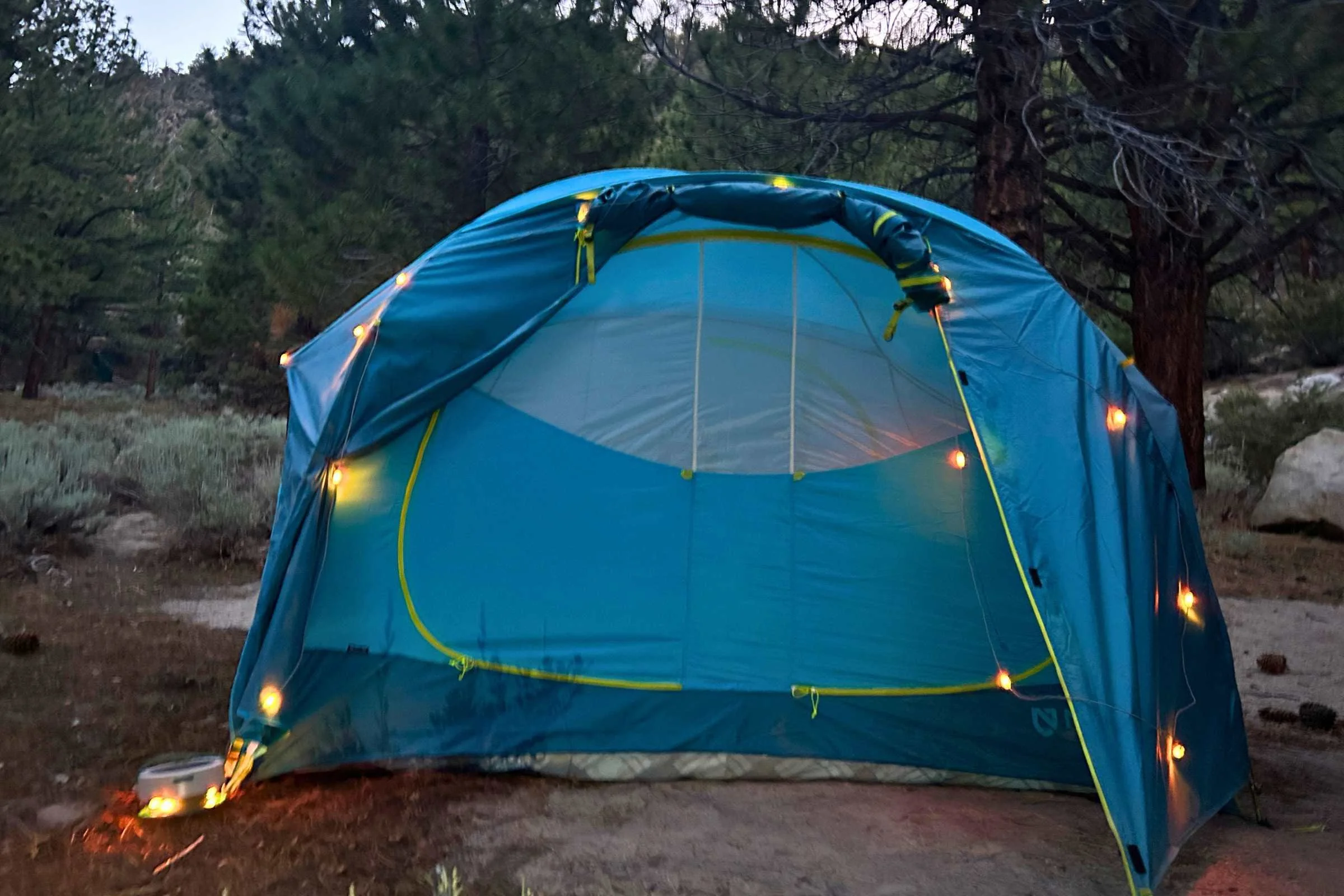   NEMO Aurora Highrise camping tent illuminated at dusk at forest campsite  