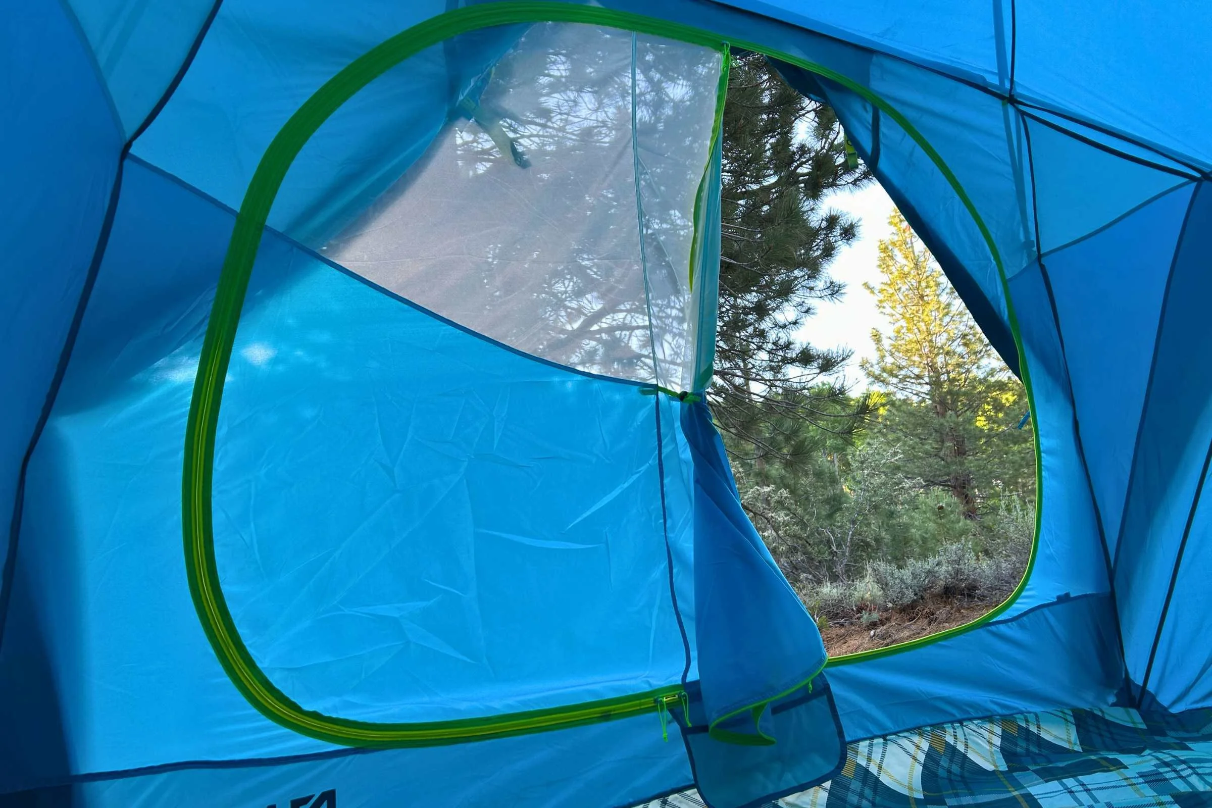   Partially open door of NEMO Aurora Highrise tent showing mesh panel and campsite view from inside the tent  