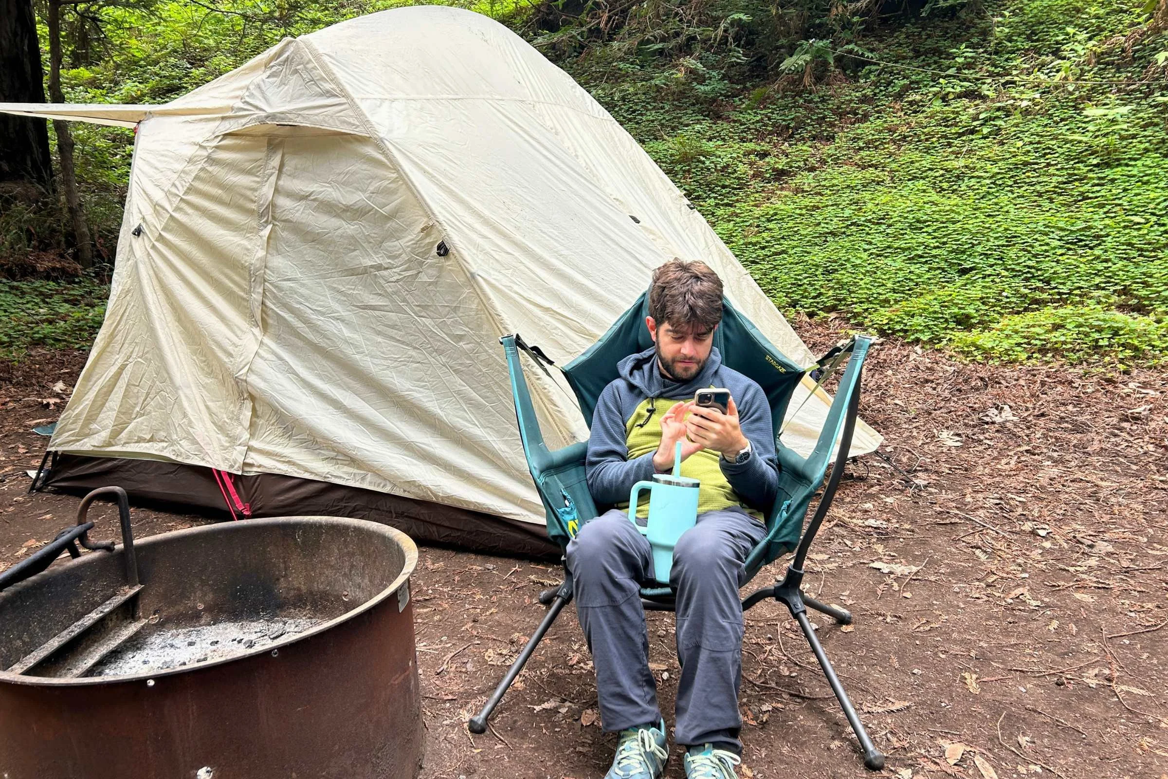   Camper relaxing in a camp chair beside Snow Peak Alpha Breeze tent at established campground  