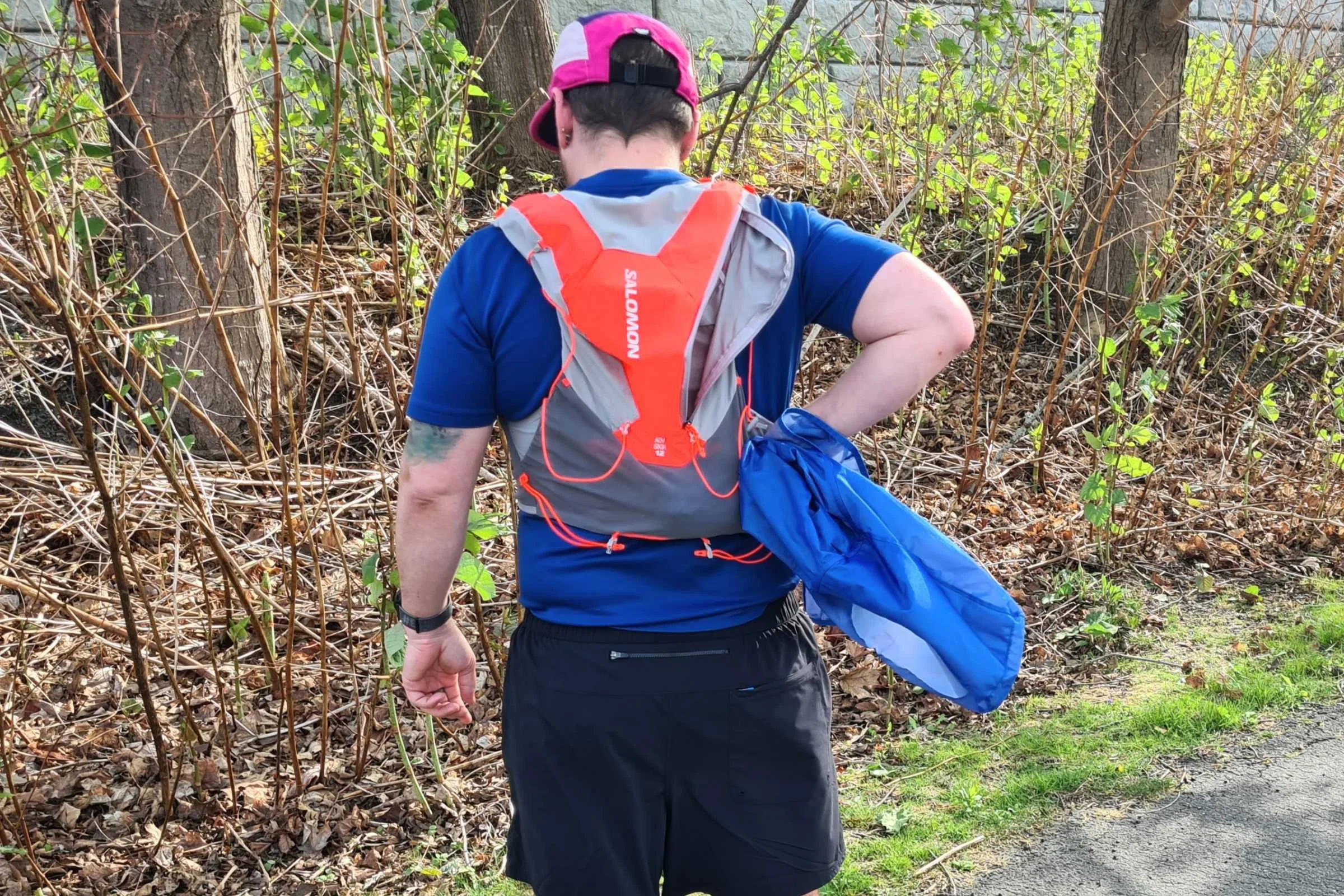   Rear view of runner wearing Salomon Adv Skin 12 hydration vest on wooded trail  