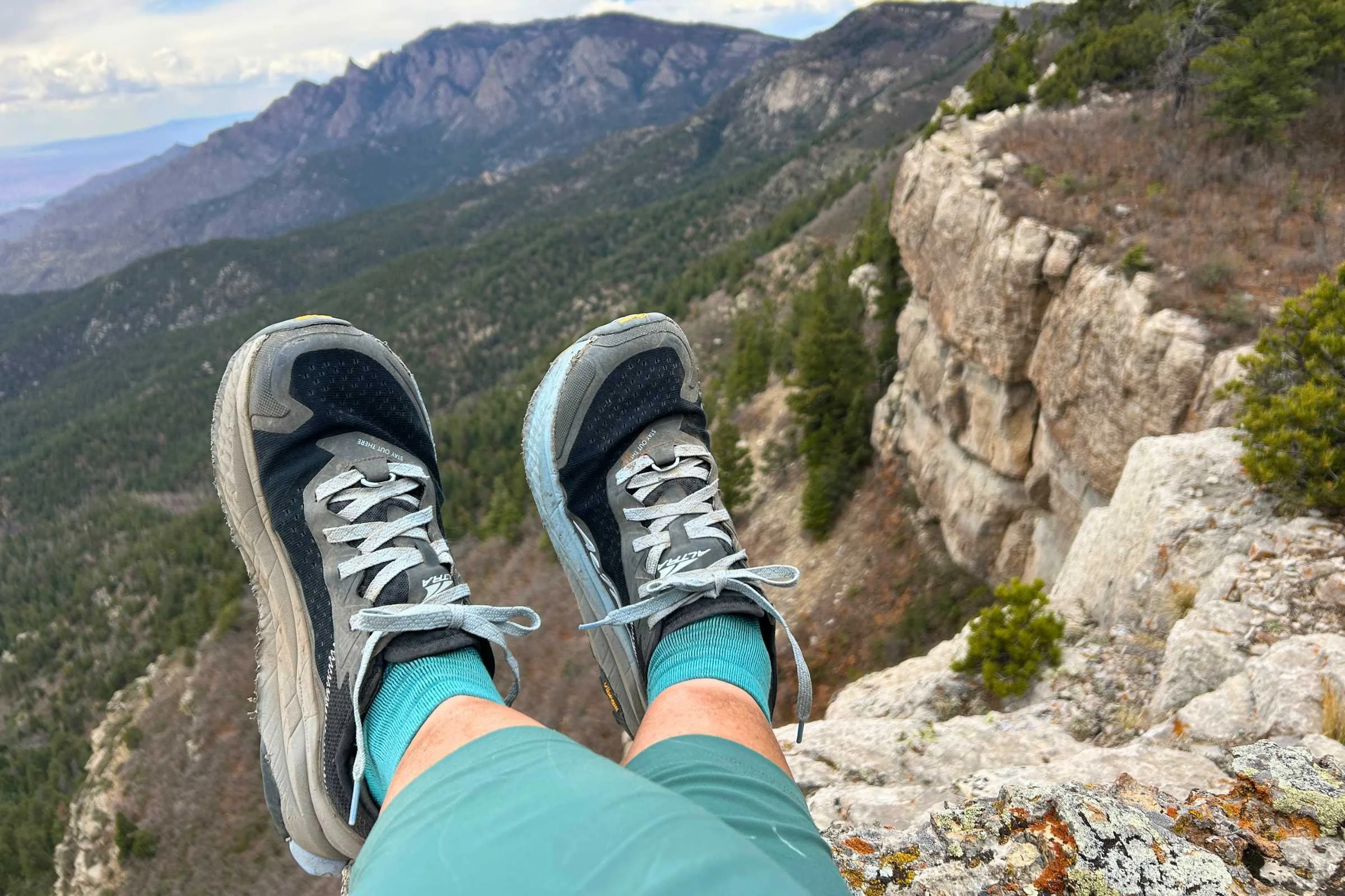   Altra Olympus 6 trail running shoes overlooking mountain landscape from rocky cliff edge  