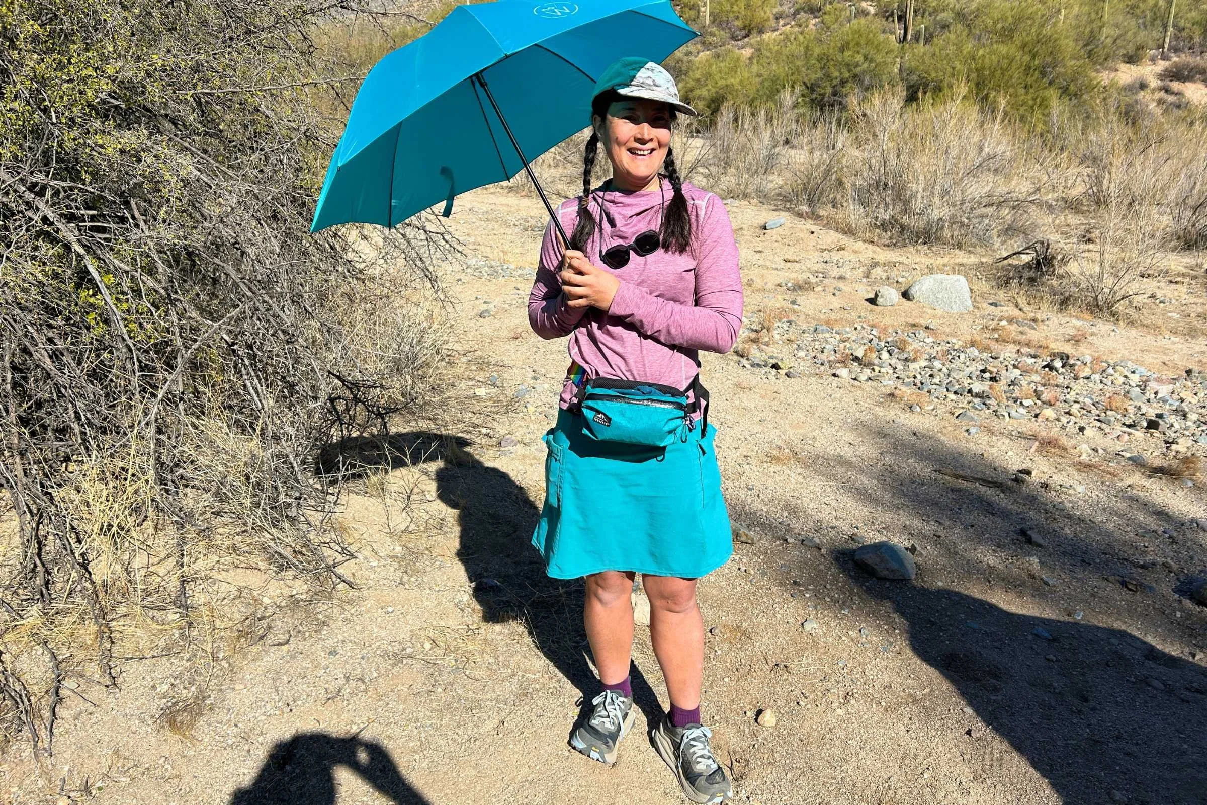   Hiker with an umbrella wearing Altra Olympus 6 trail running shoes on desert trail  