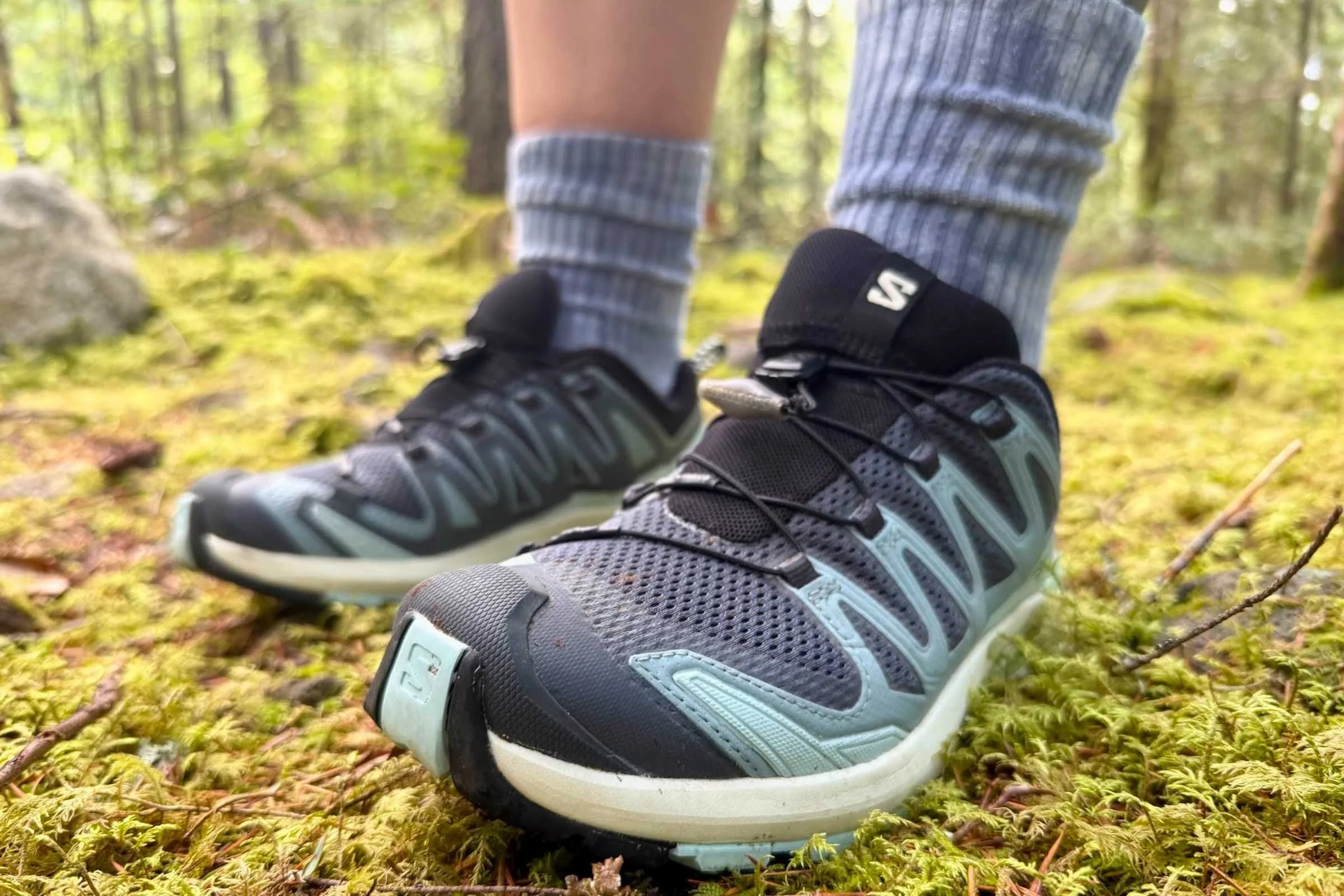   Close-up of Salomon XA Pro 3D V9 GORE-TEX trail running shoes on mossy forest trail  
