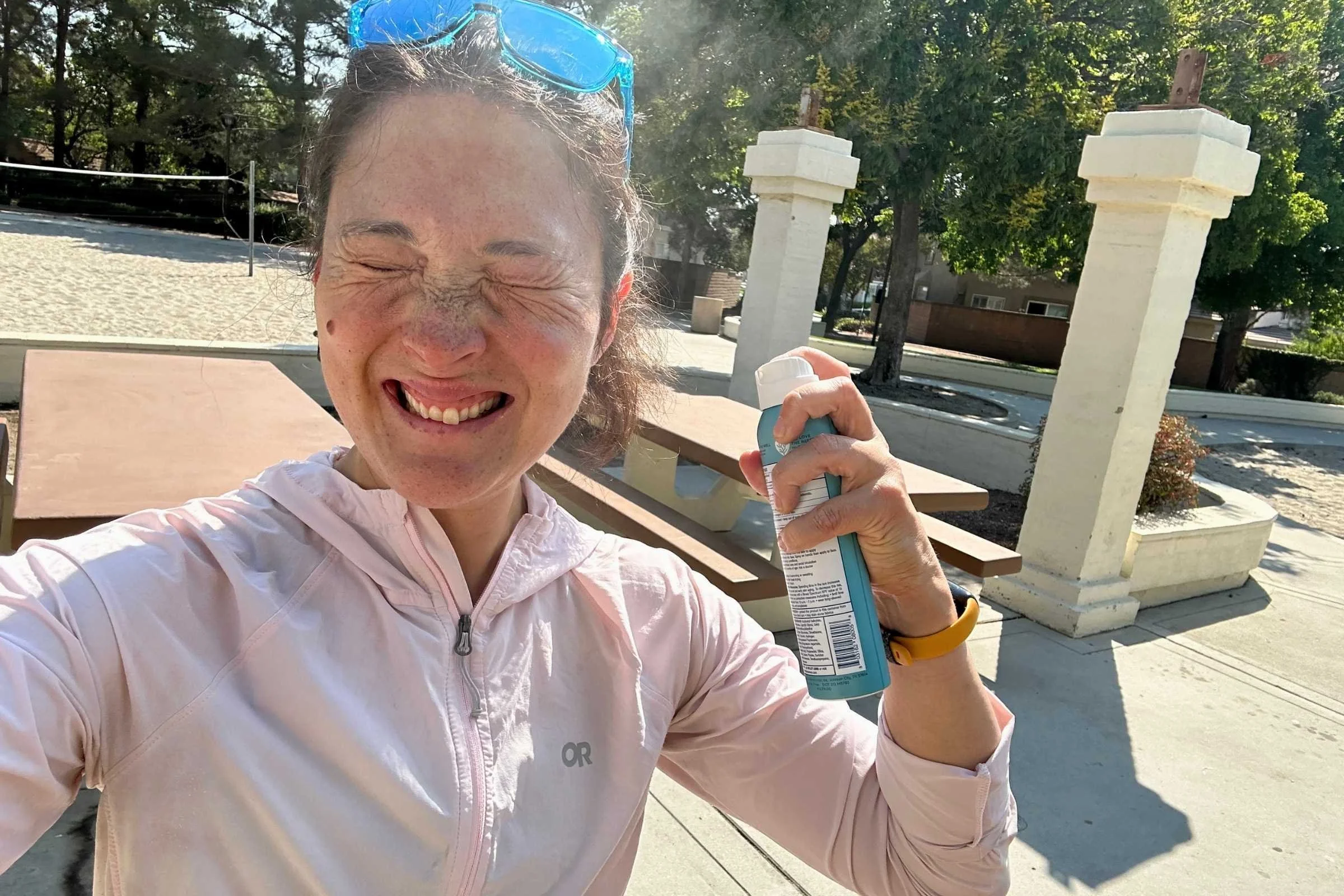   Woman wearing Outdoor Research Astroman Sun Hoodie while holding sunscreen outdoors  