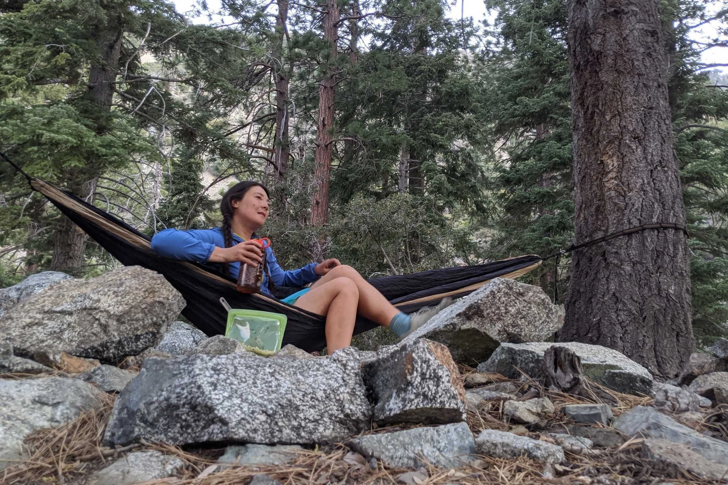   Author Liz Thomas sitting in a hammock while testing the Outdoor Research Astroman Air sun hoody in the San Gabriel mountains of California.   Photo courtesy Liz Thomas.  