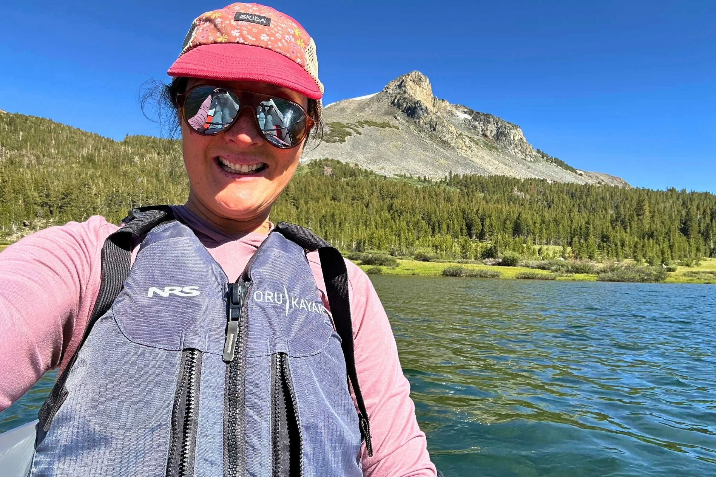   Woman wearing life jacket over Free Fly Shade Hoodie while kayaking on alpine lake  