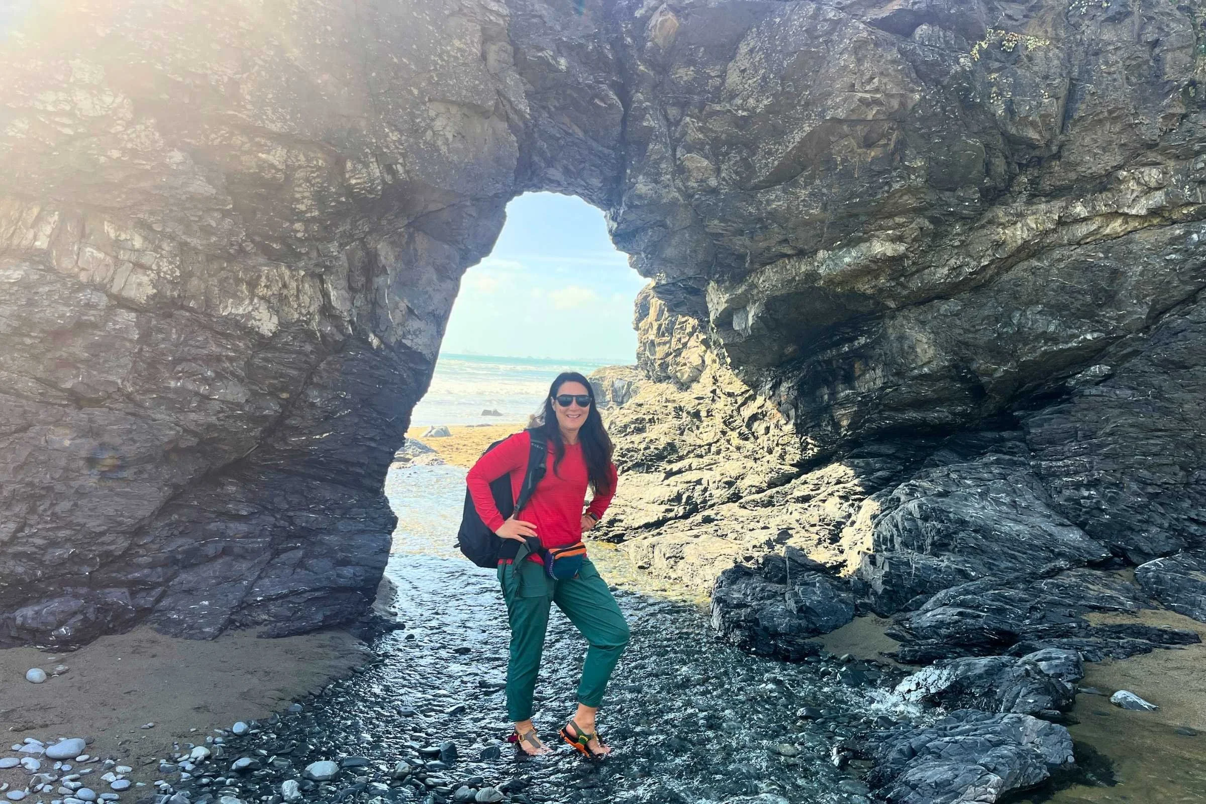   Hiking on the beach through a natural arch wearing the Title Nine Upland Long Sleeve Sun Shirt.  