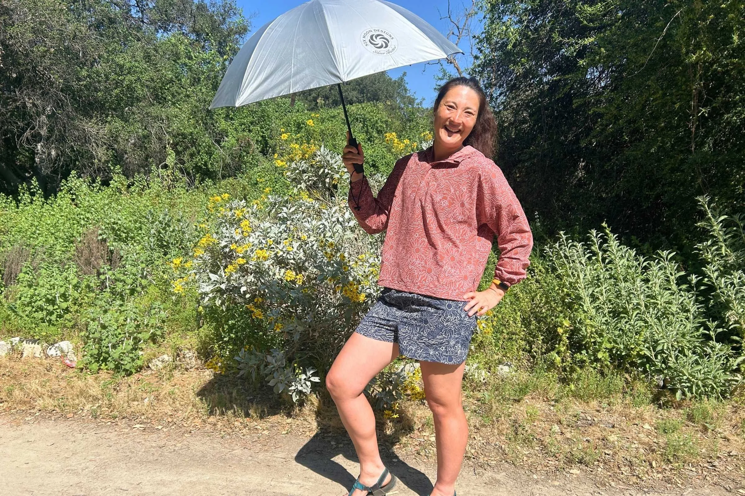   Woman wearing Royal Robbins Salathe Sun Shirt holding a sun umbrella on a trail  