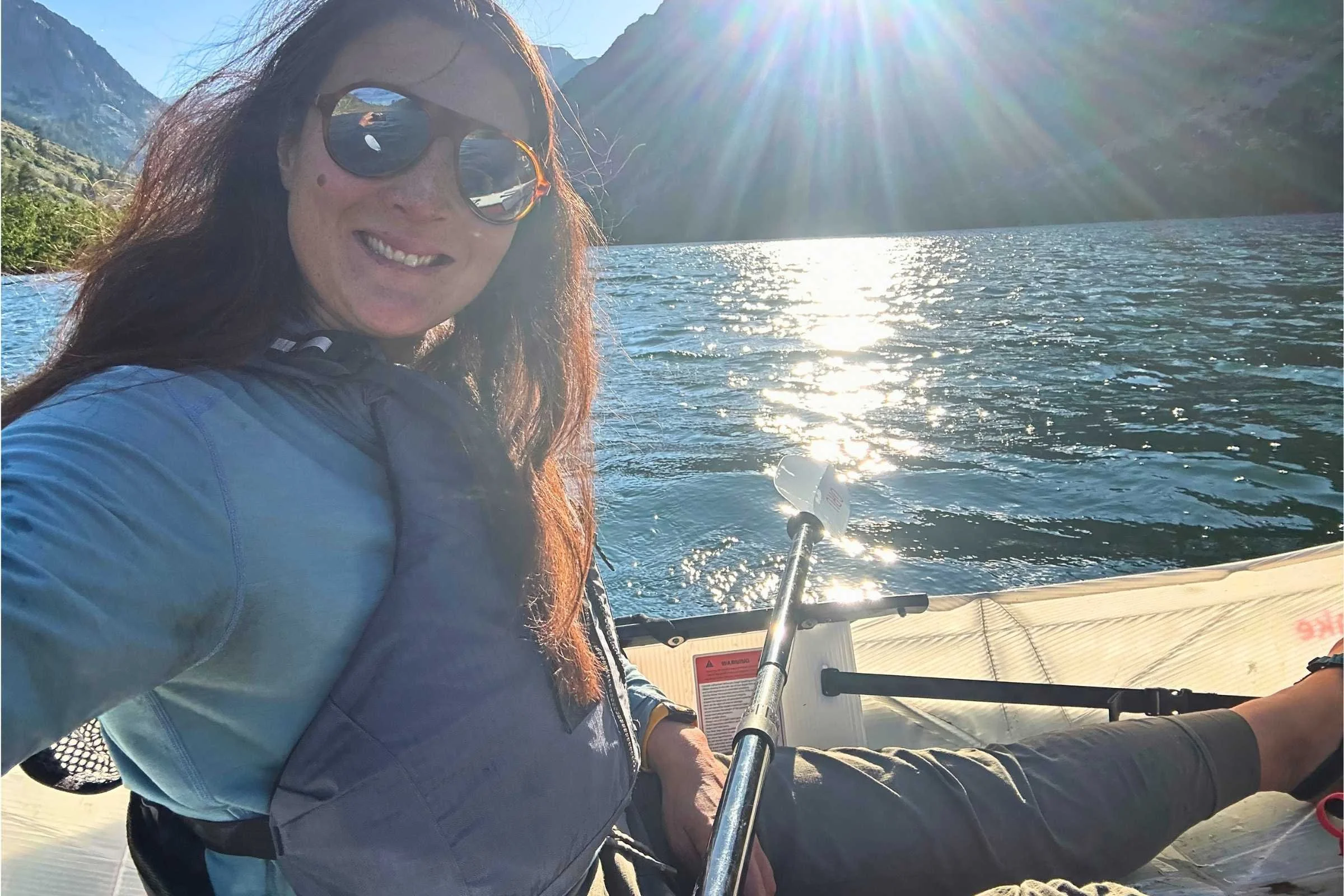   Woman wearing Ridge Merino Solstice Pro Hoodie while kayaking on alpine lake  