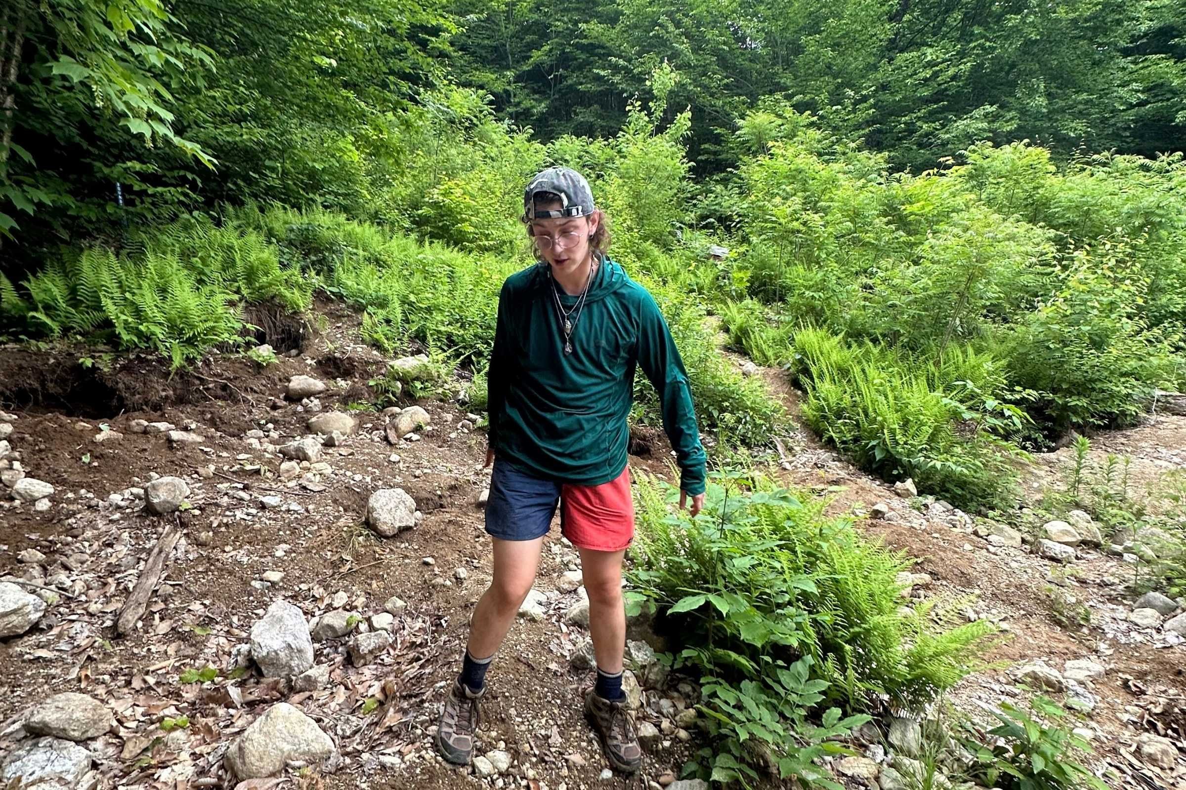   Hiker wearing Outdoor Research Echo Hoodie on rocky forest trail  