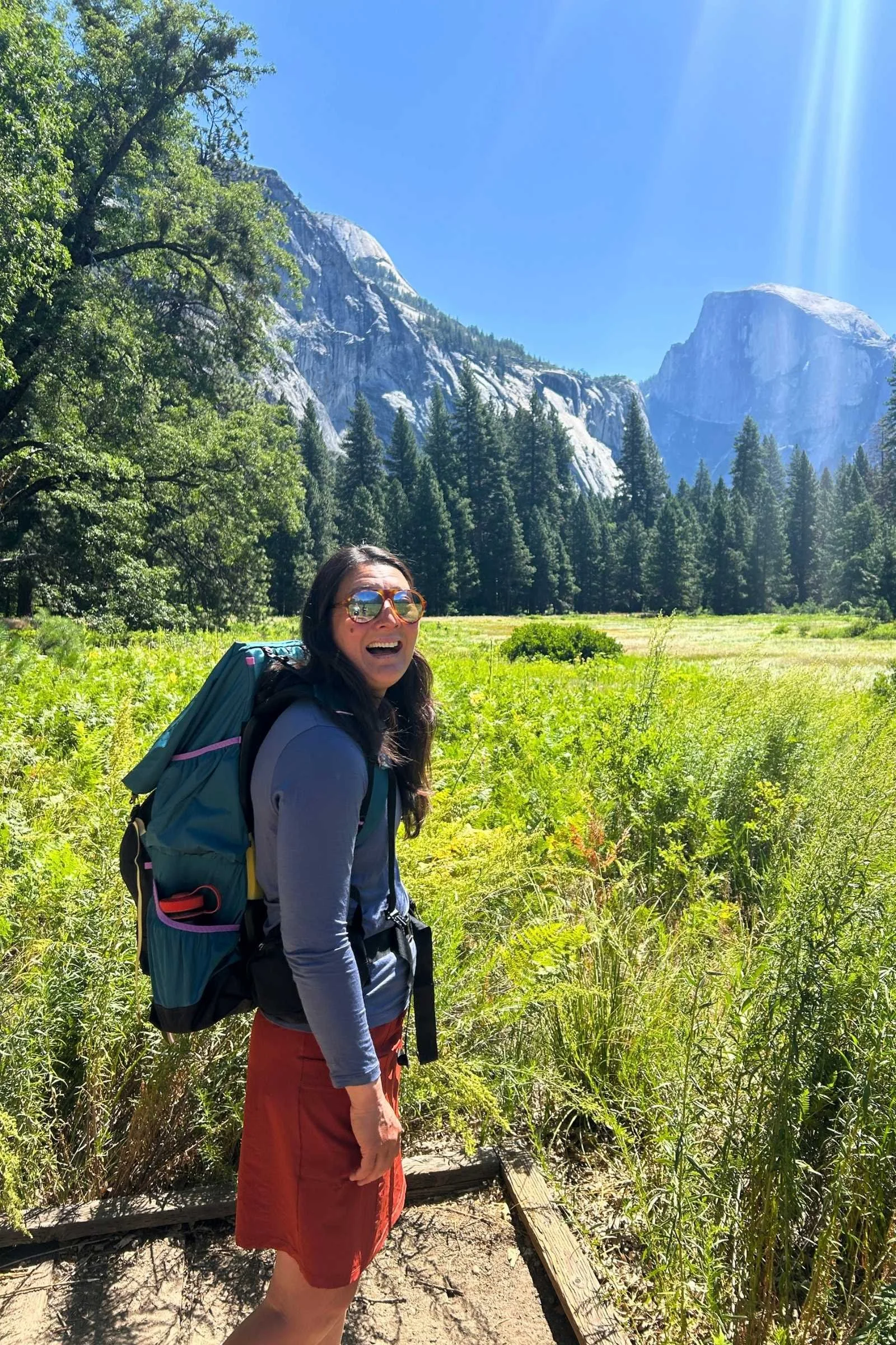   Woman wearing Smartwool Active UL Sun Hoodie with backpack in Yosemite Valley with Half Dome in the background  