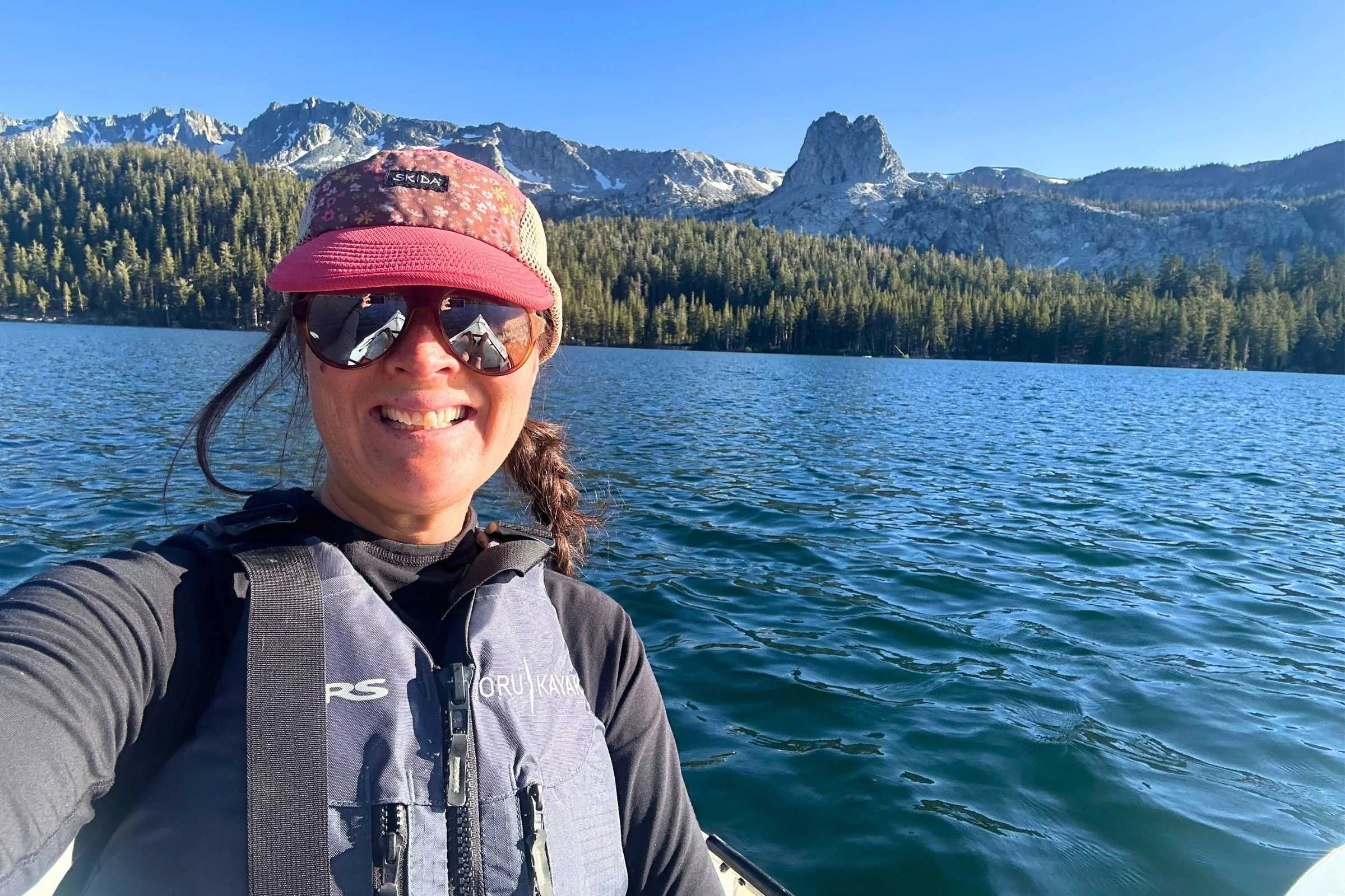   Woman wearing a life jacket over The North Face Sunriser Sun Hoodie while kayaking on alpine lake  