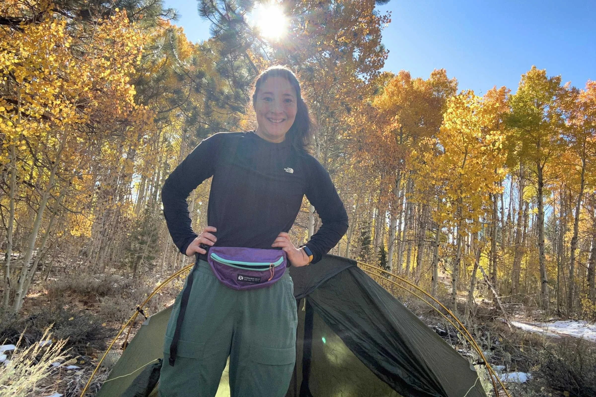   Woman wearing The North Face Sunriser Sun Hoodie at campsite surrounded by autumn trees  