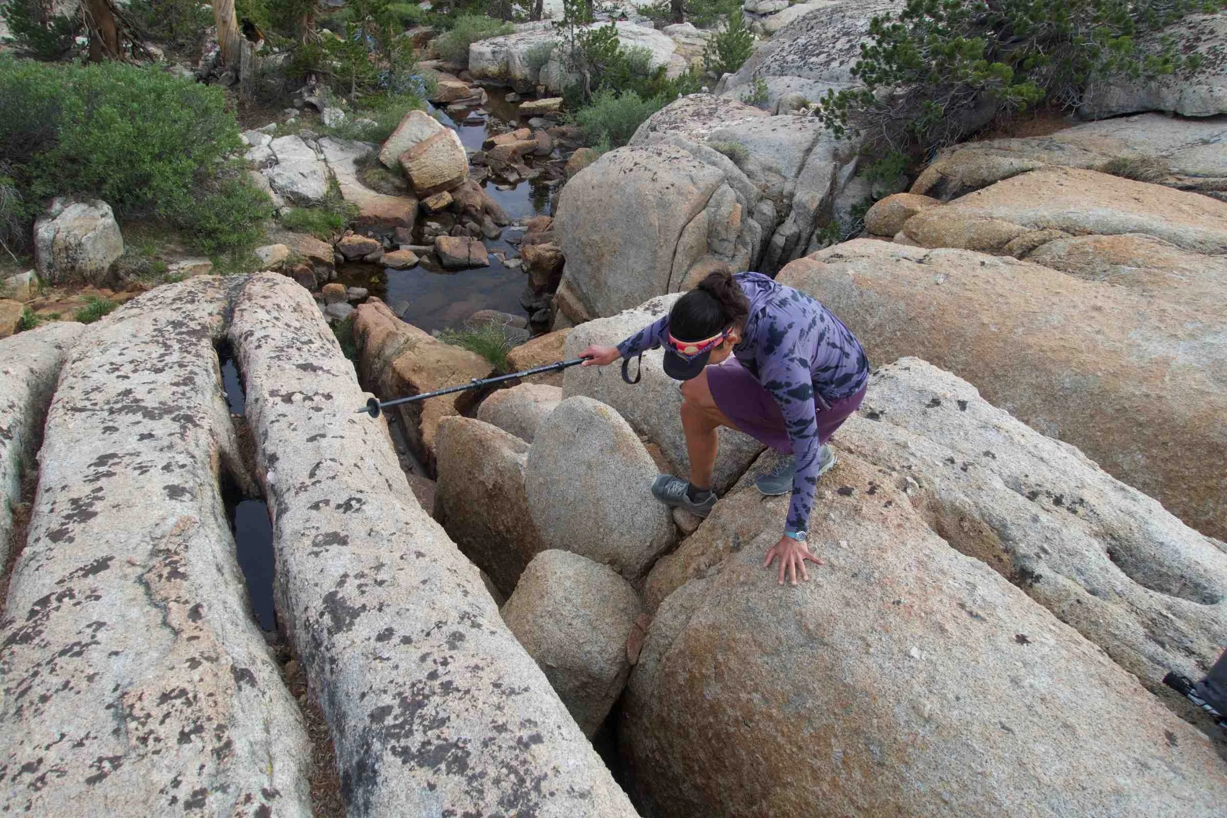   Woman scrambling over granite boulders while wearing Mountain Hardwear Crater Lake Hoody  