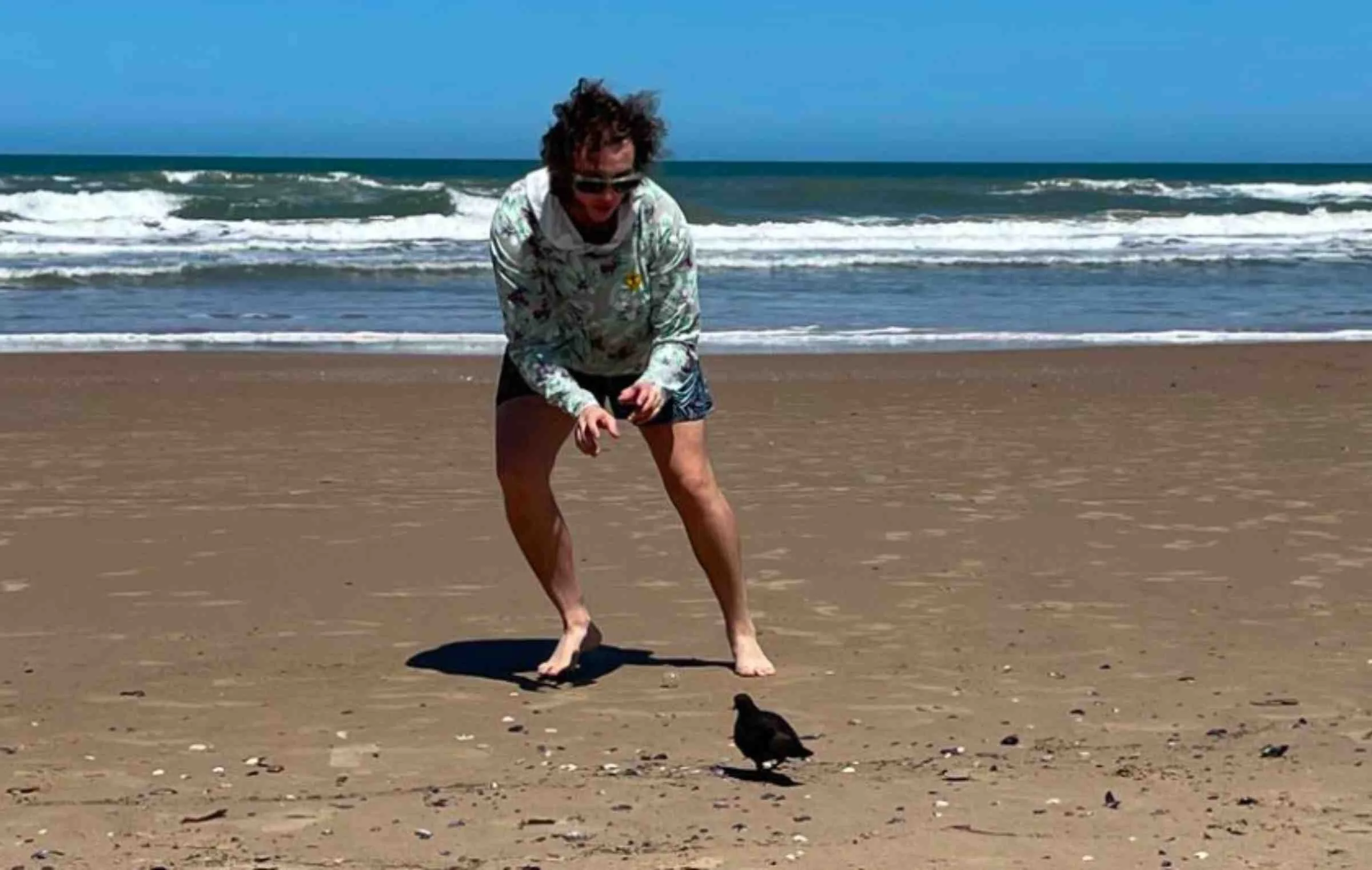   Person wearing Town Shirt Sun Hoodie on the beach near the ocean  
