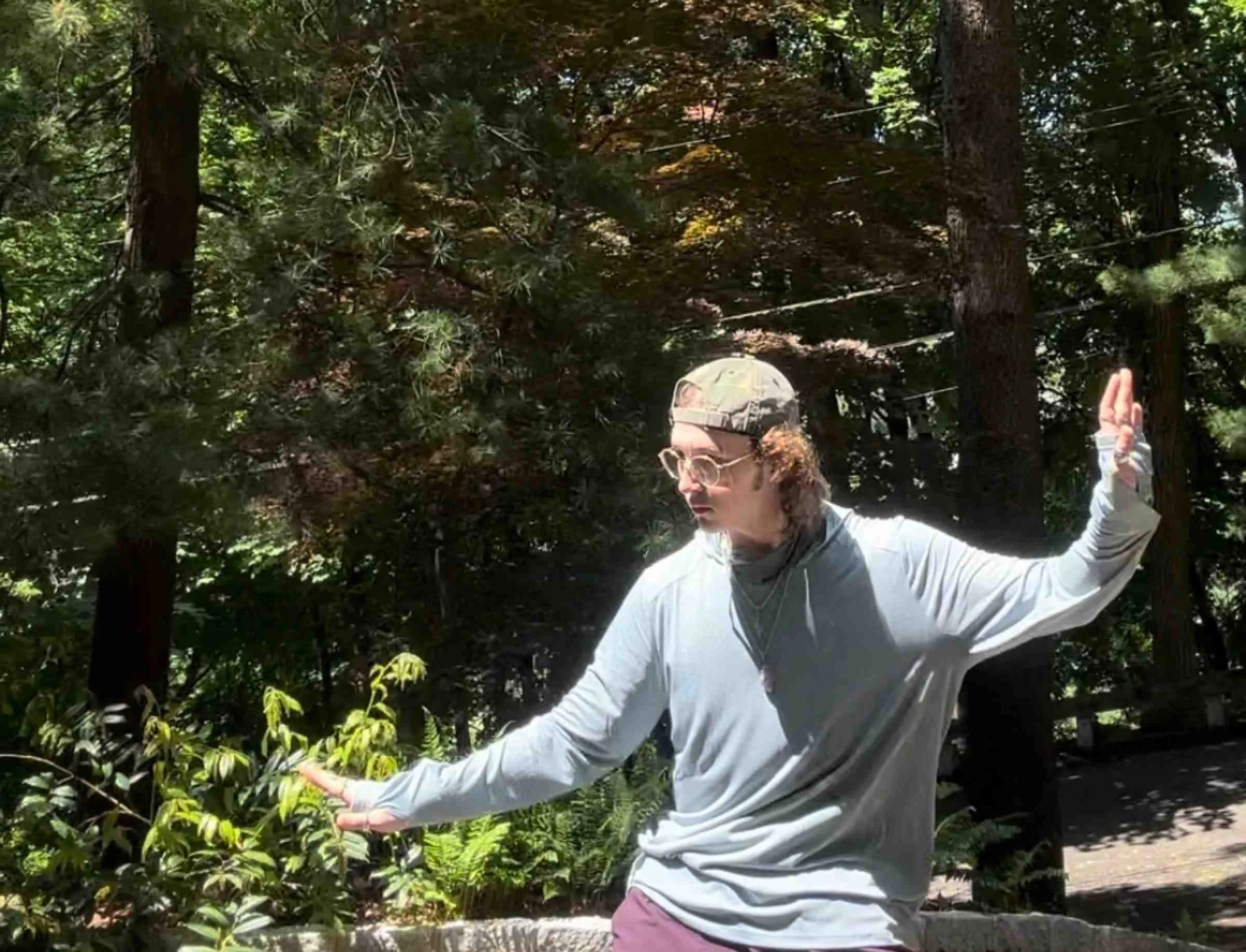   Person wearing Free Fly Shade Hoodie with arms extended in wooded area  