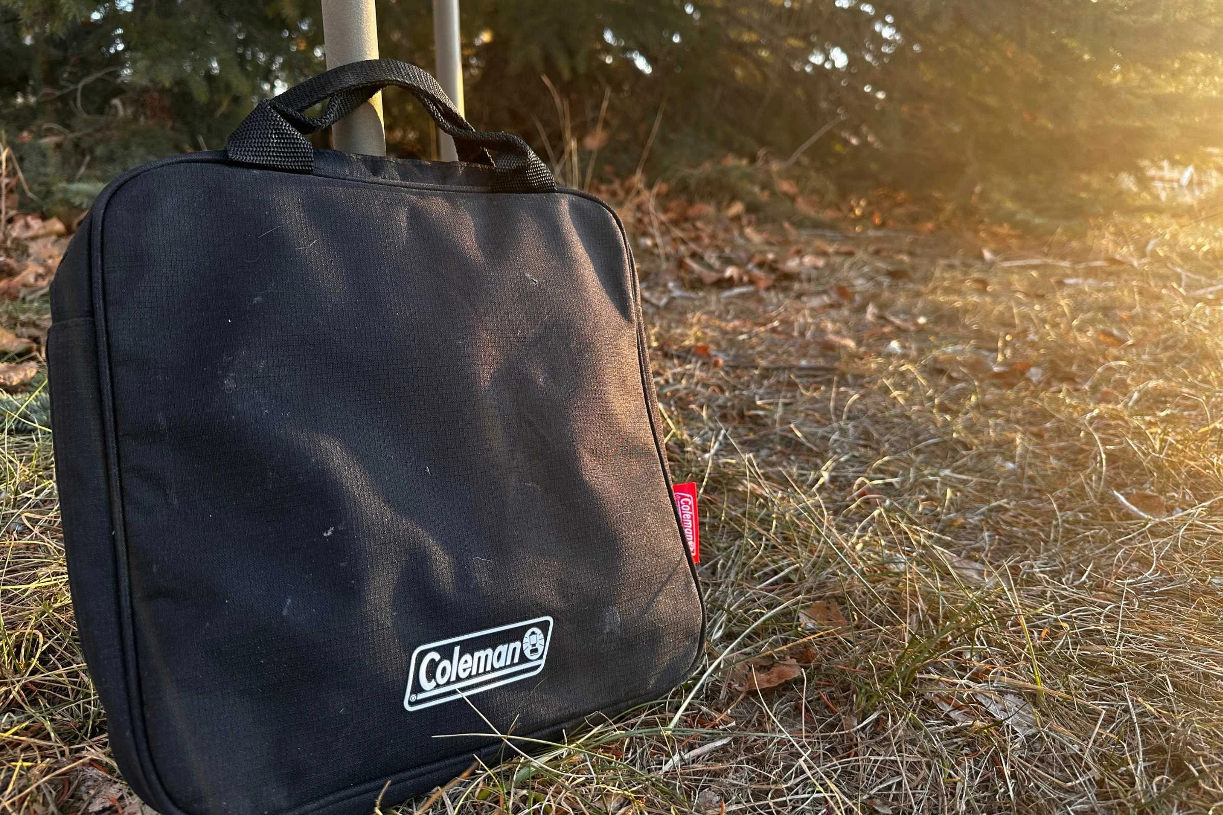   The Coleman Cascade 3-in-1 camp stove in it’s carrying case leaned up against a pole outside  