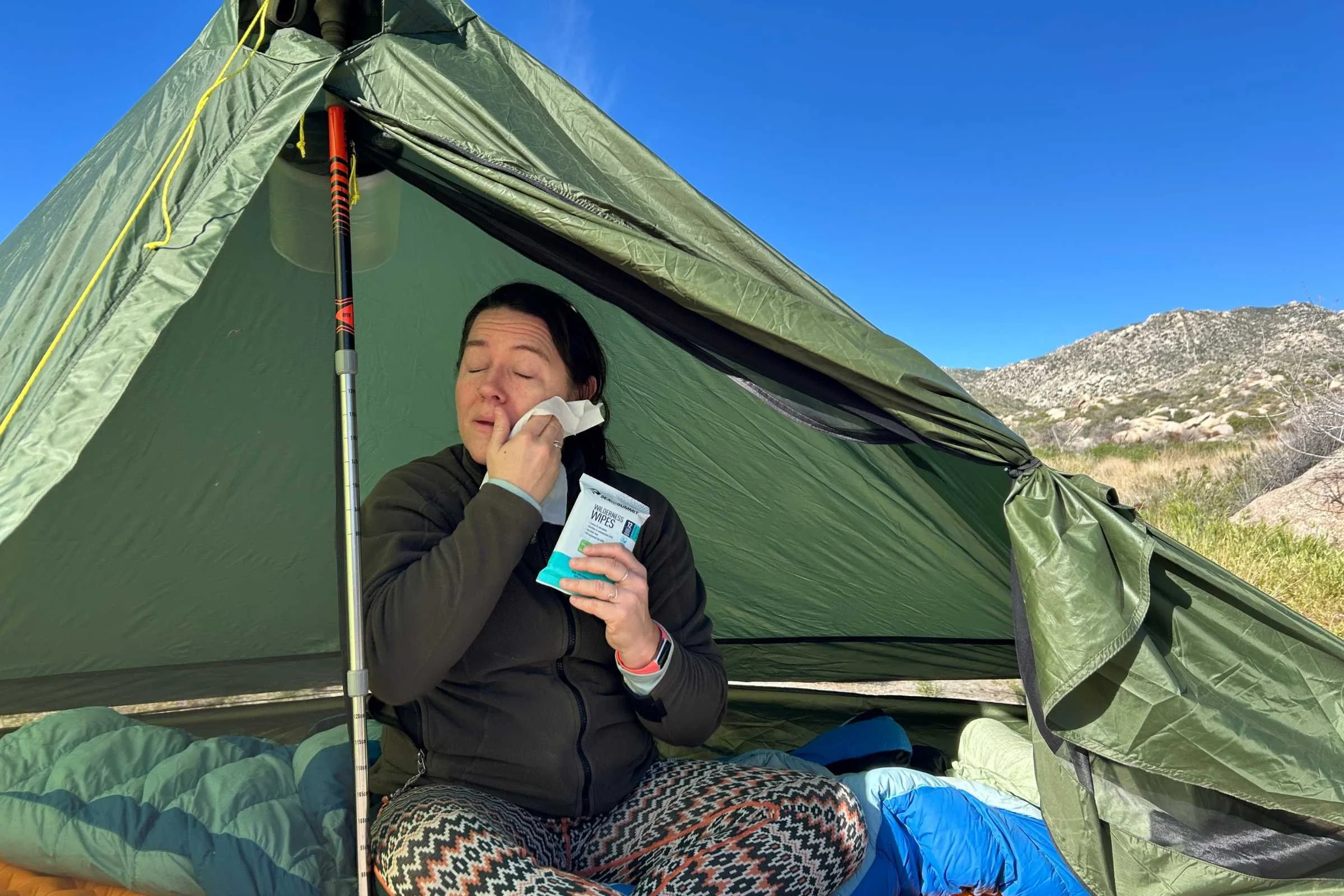   Tester in a tent using Sea to Summit Wilderness Wipes to clean their face  