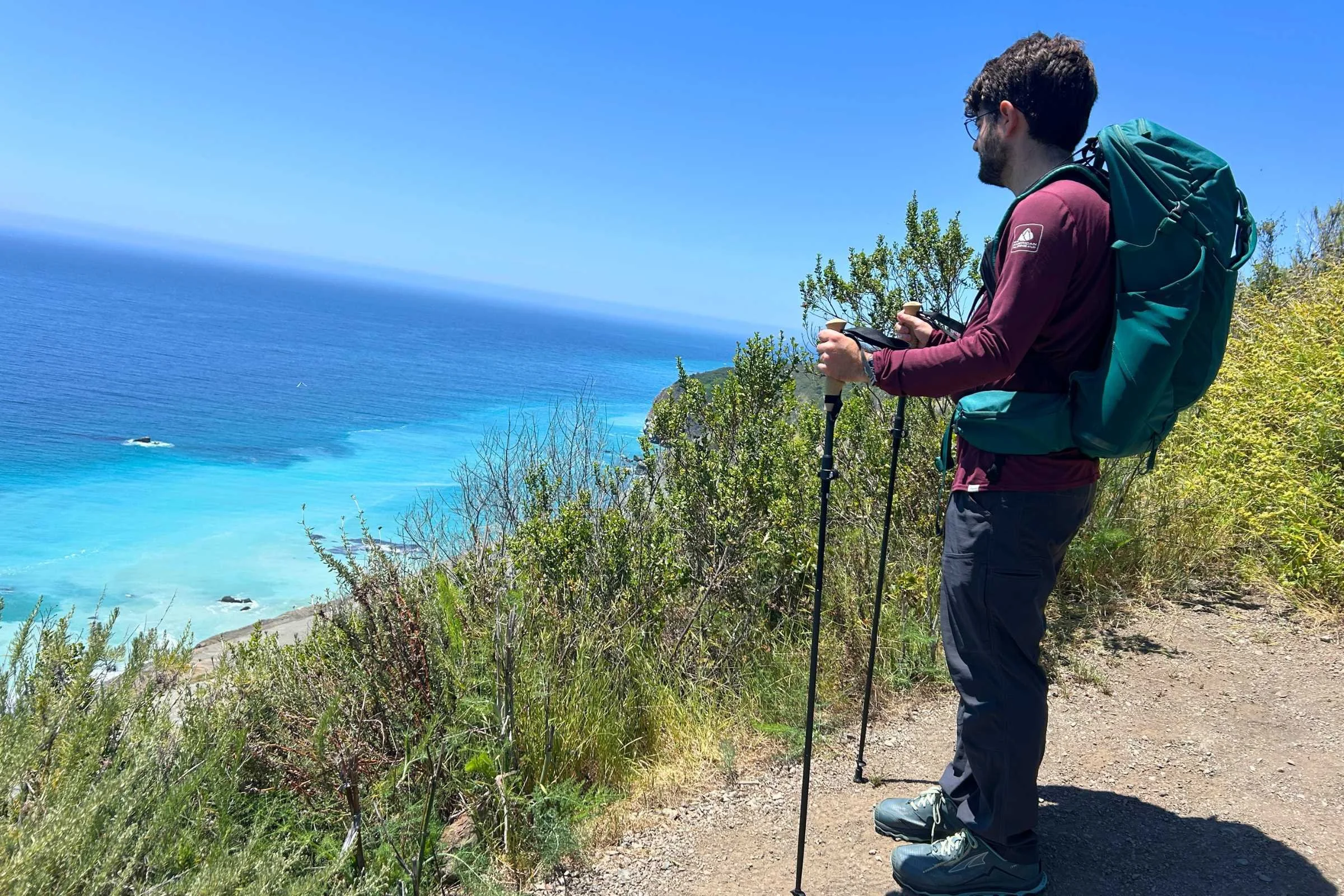   Man on a trail overlooking a cerulean ocean using the Gossamer Gear FT3 trekking poles  