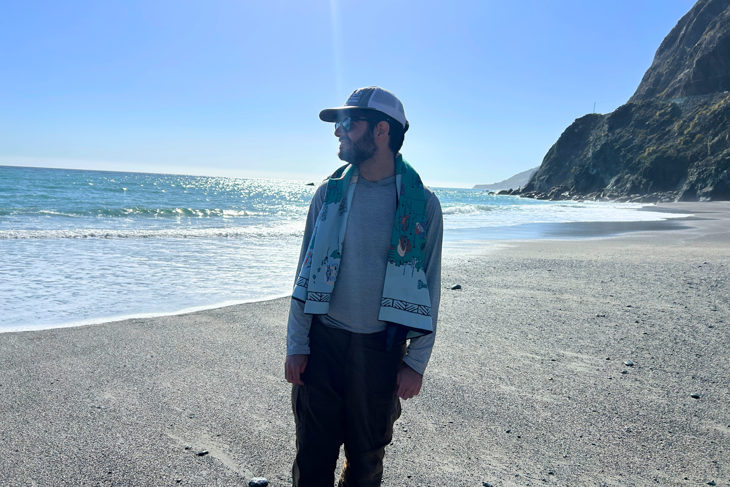   Man at beach with Nomadix Ultralight towel draped over his shoulders  