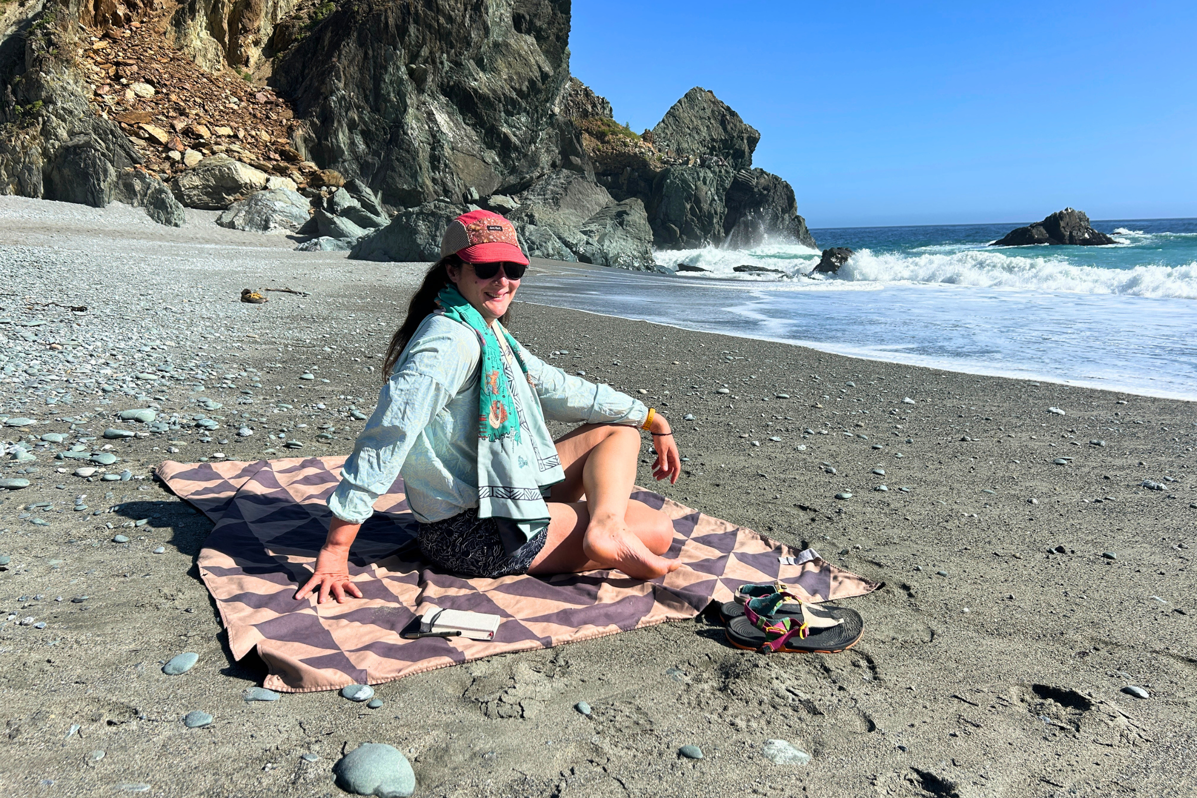   Woman sitting on a Nomadix Ultralight towel on the beach  