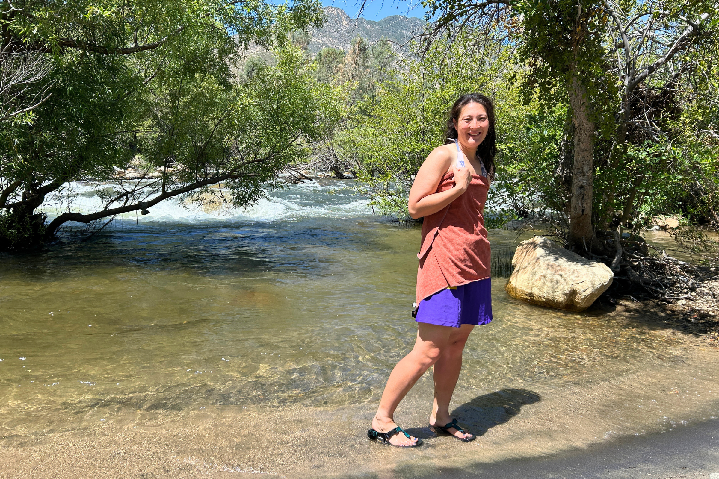   Woman drying off with REI Multi-Towel Deluxe after swimming in a river  